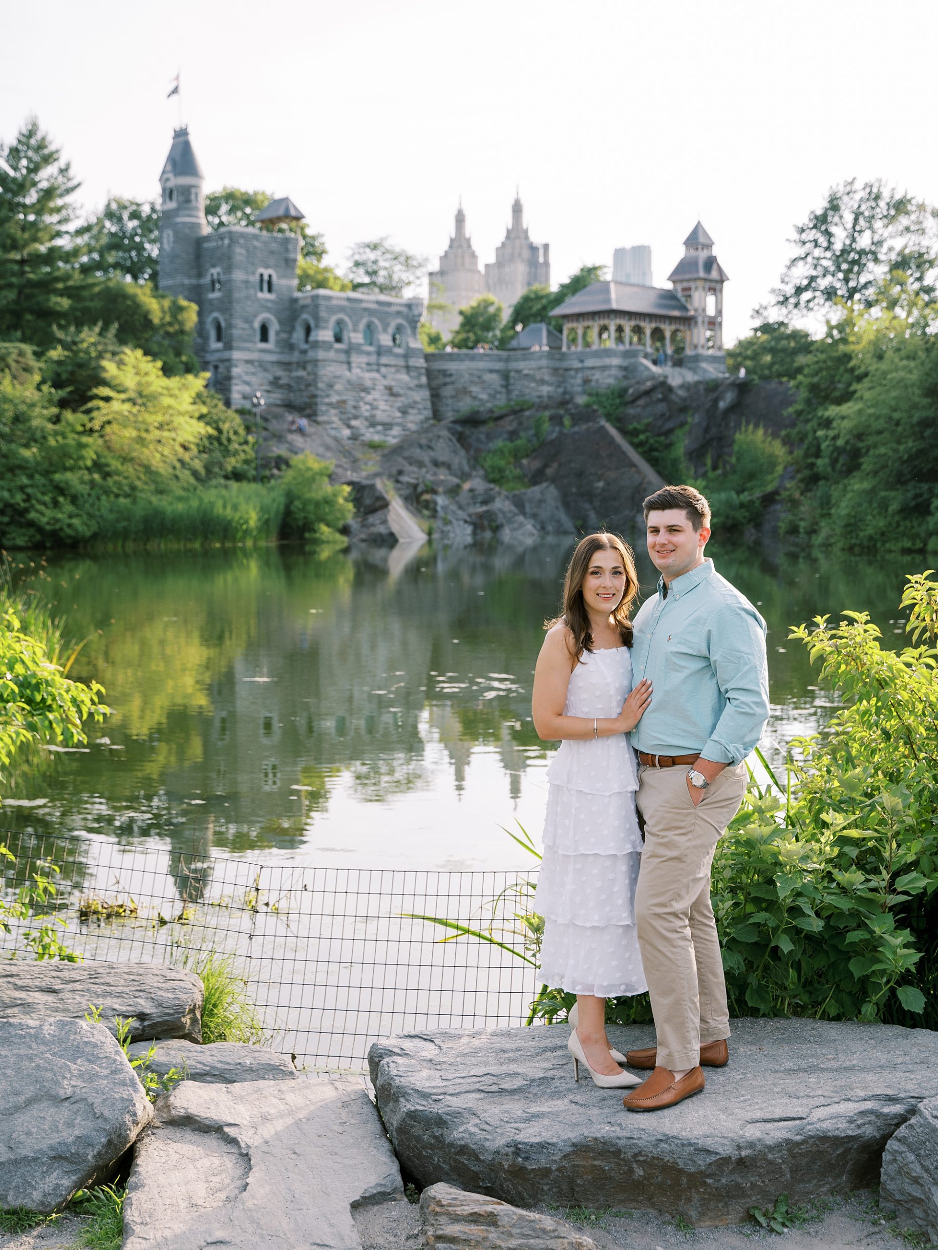 engaged couple stands on rocks at Central Park