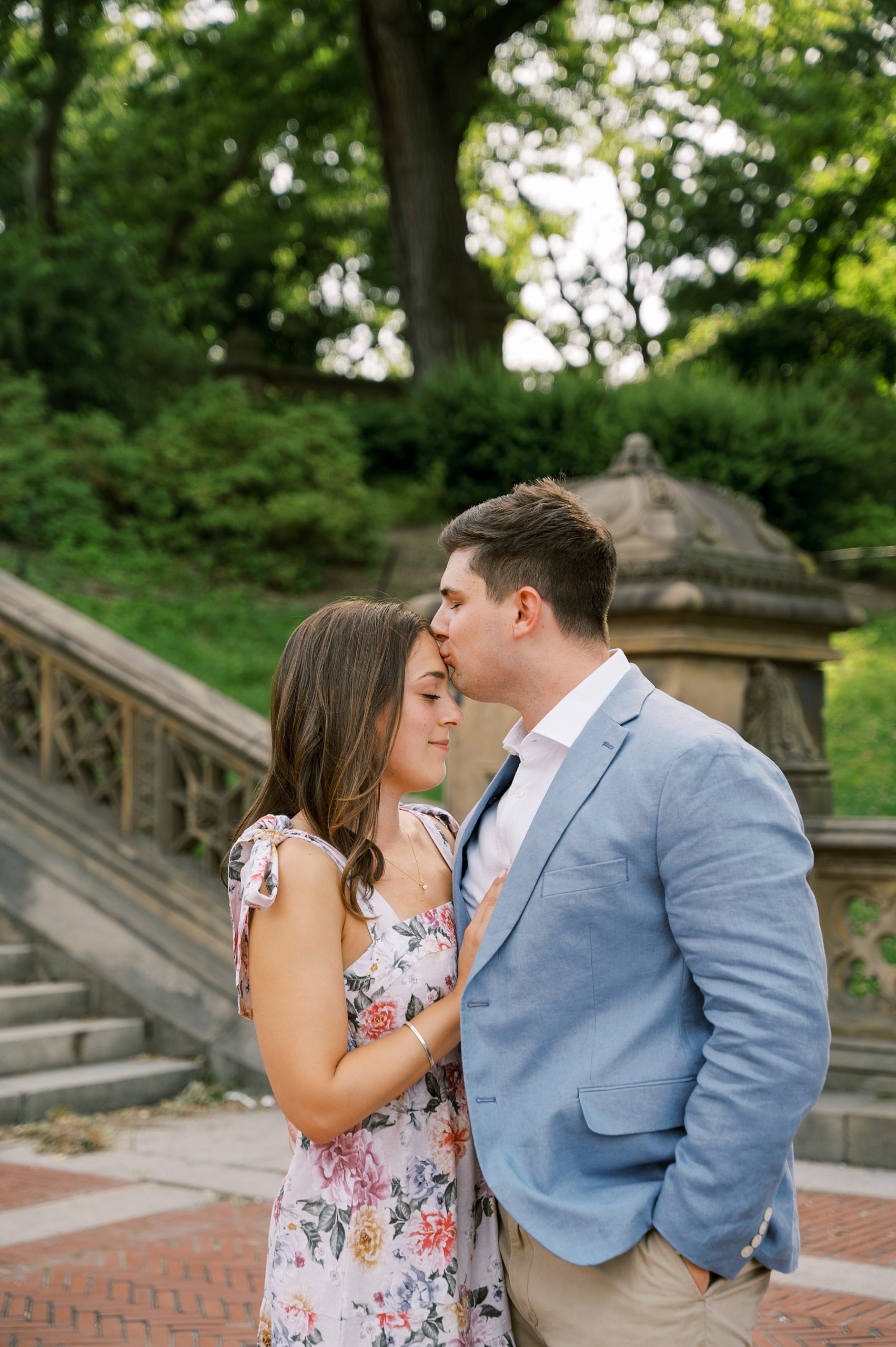 groom kisses bride's forehead during Central Park engagement session