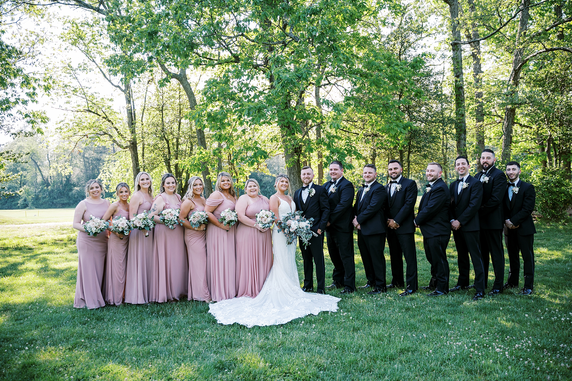 bride and groom stand with wedding party in pink and black