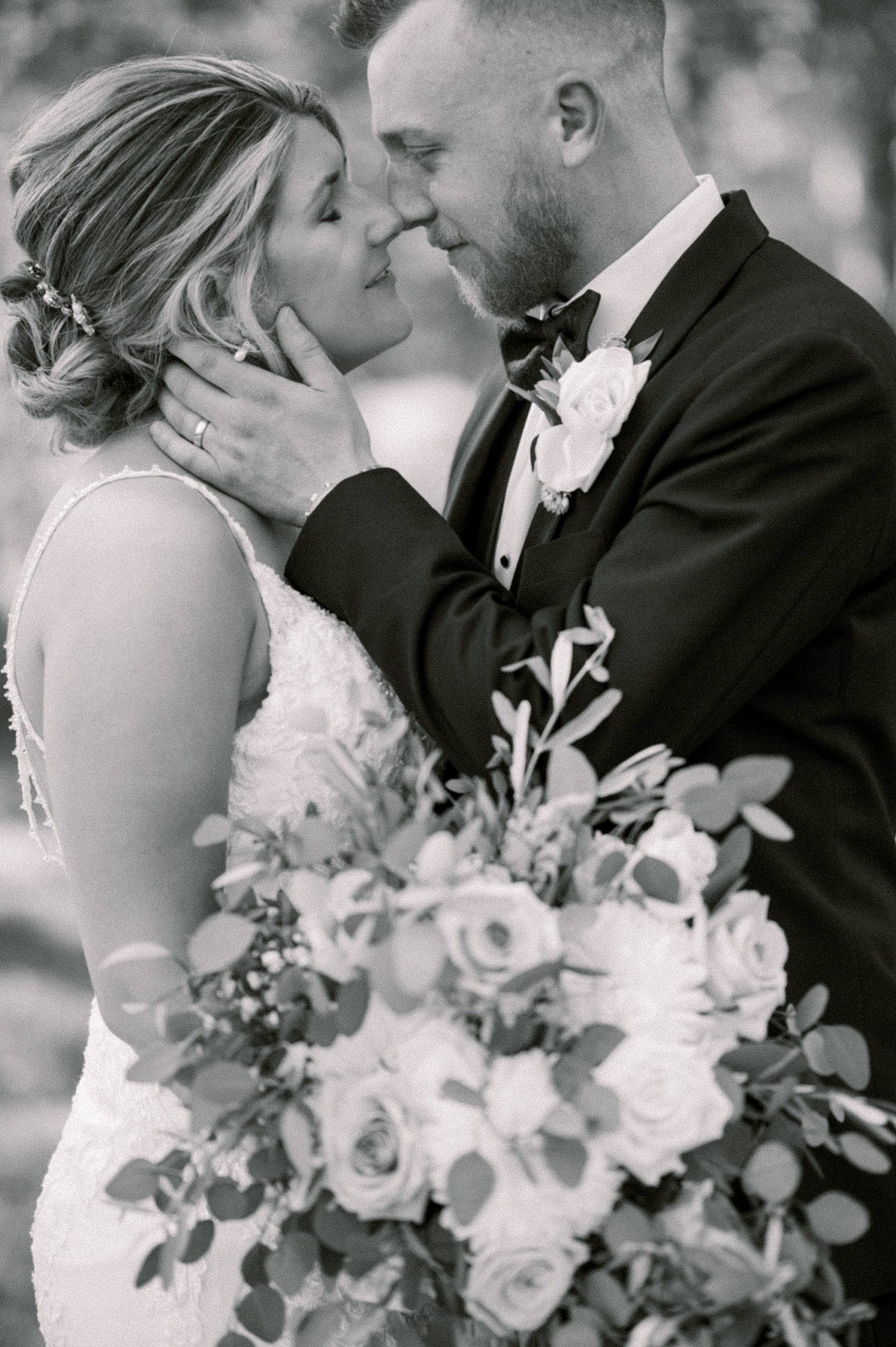 groom holds bride's chin for kiss during portraits at The Grove at Centerton