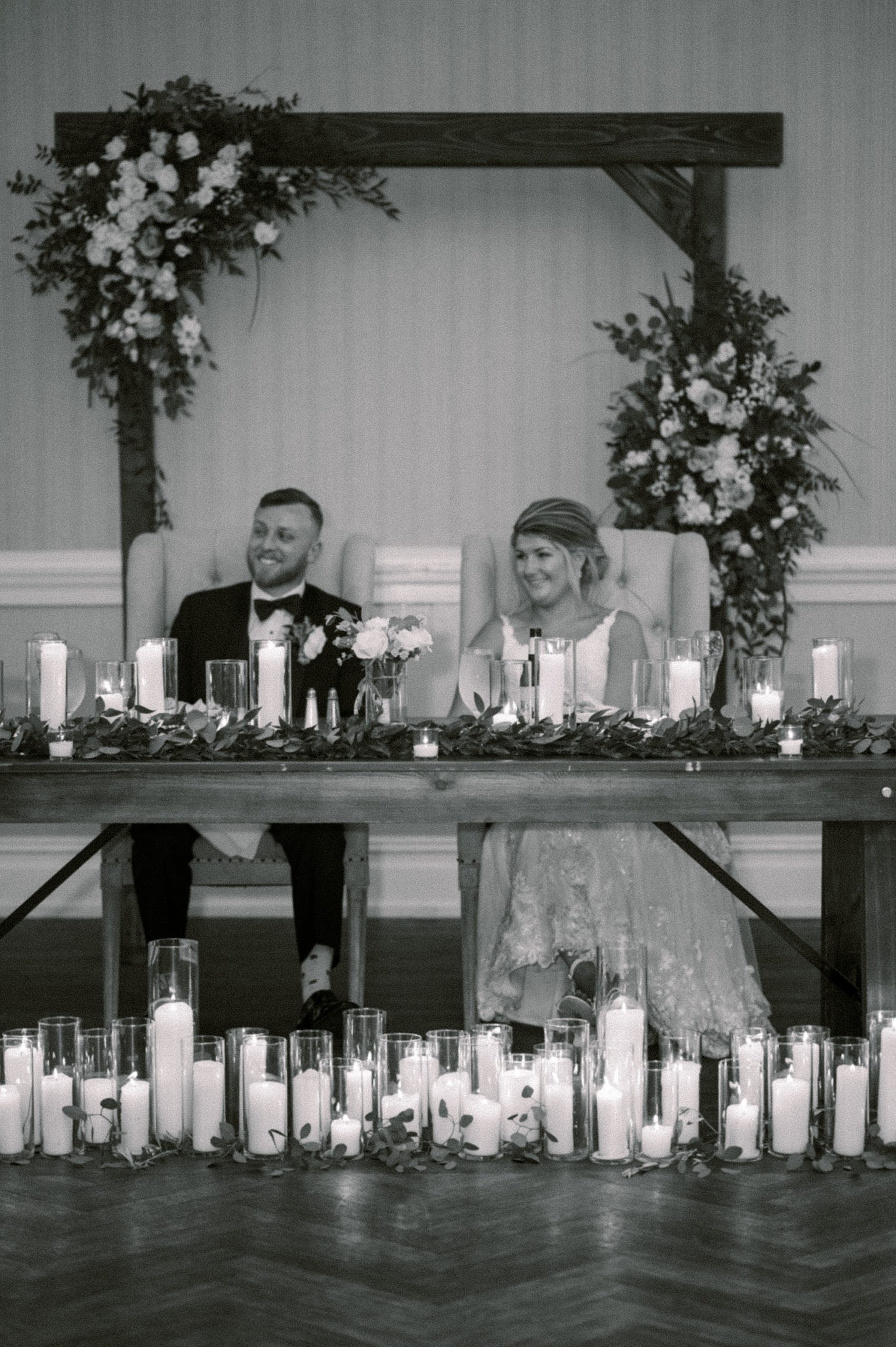 bride and groom sit at sweetheart table with candles at The Grove at Centerton