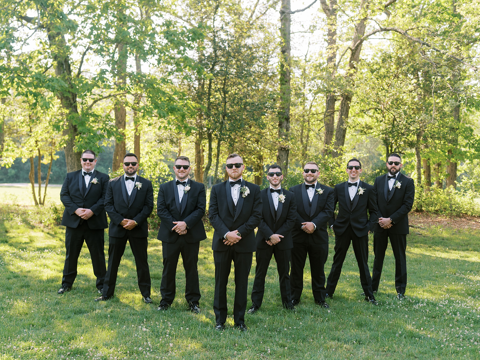 groom and groomsmen walk in suits with sunglasses at The Grove at CentertonThe Grove at Centerton