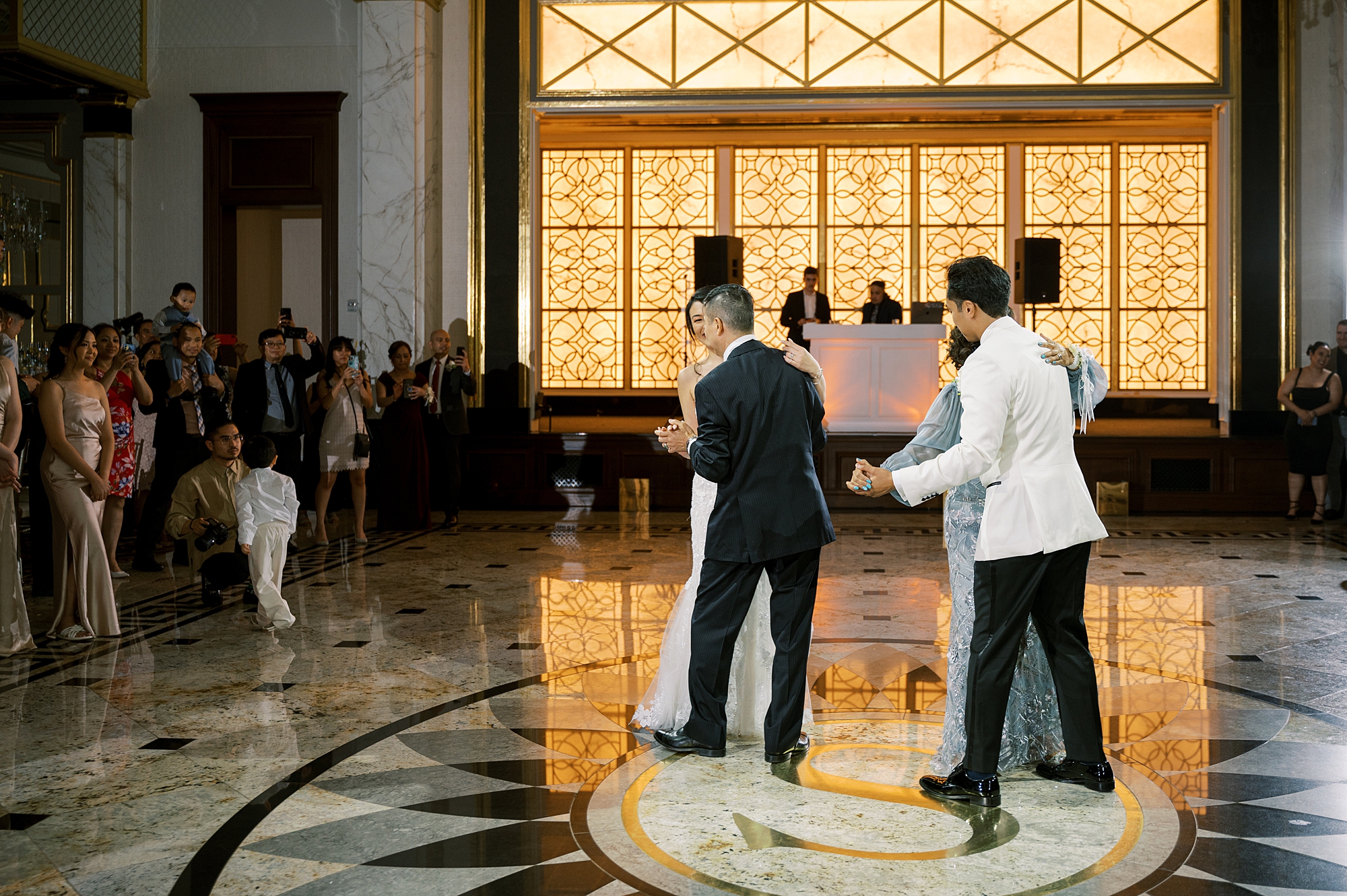 bride and groom dance with parents in ballroom