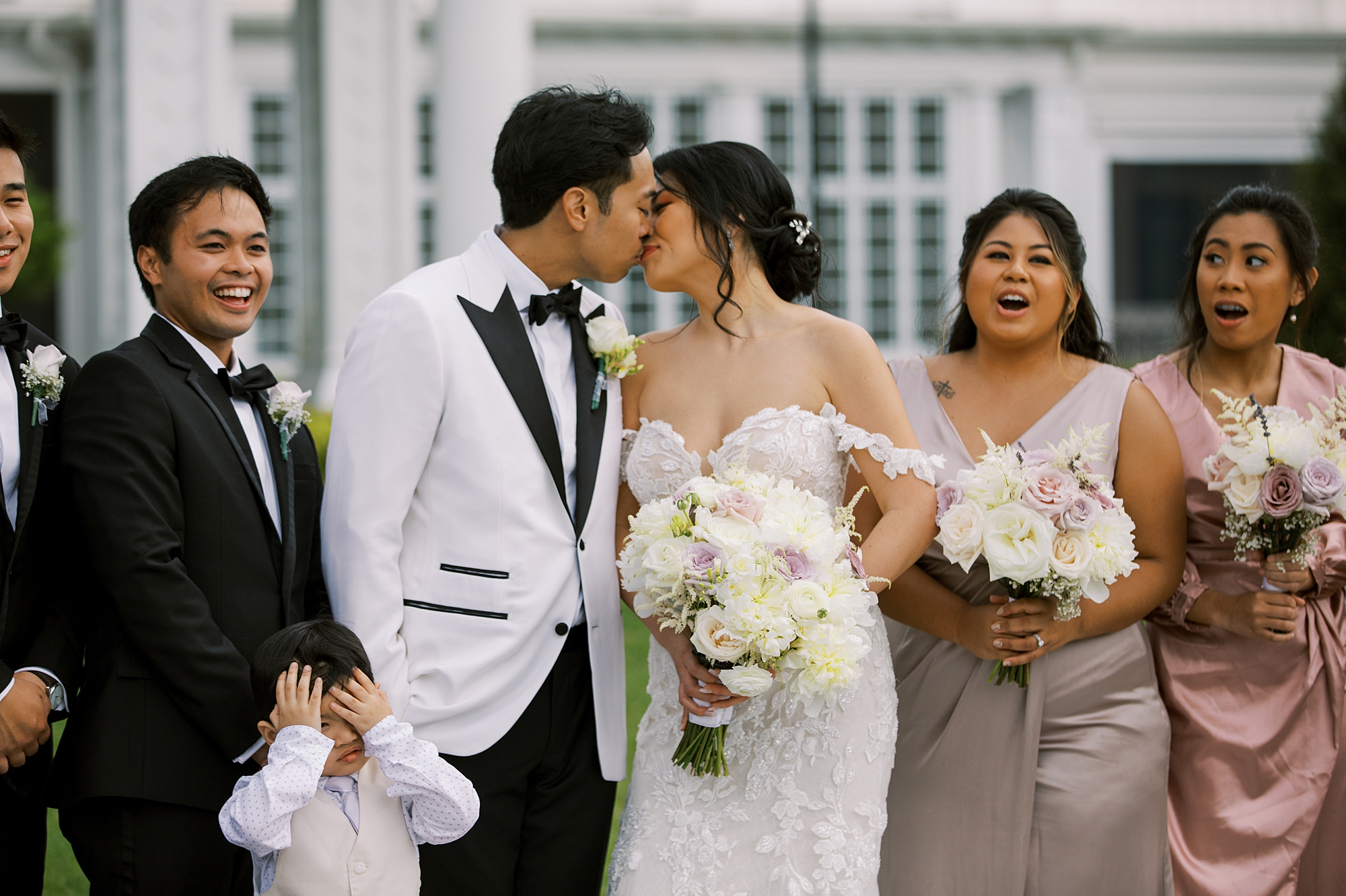 newlyweds kiss while wedding party cheers around them