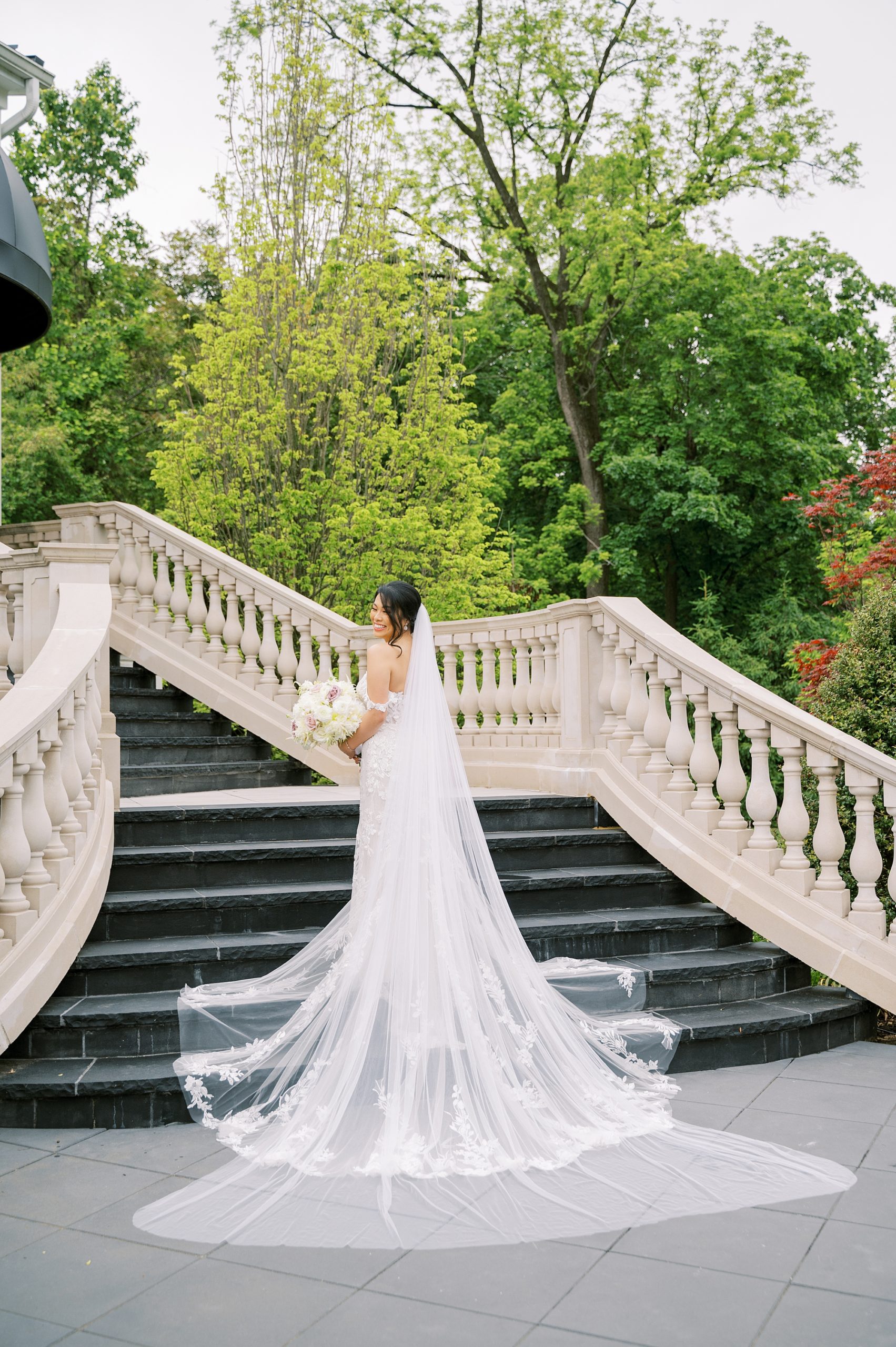 bride poses on steps at Shadowbrook at Shrewsbury