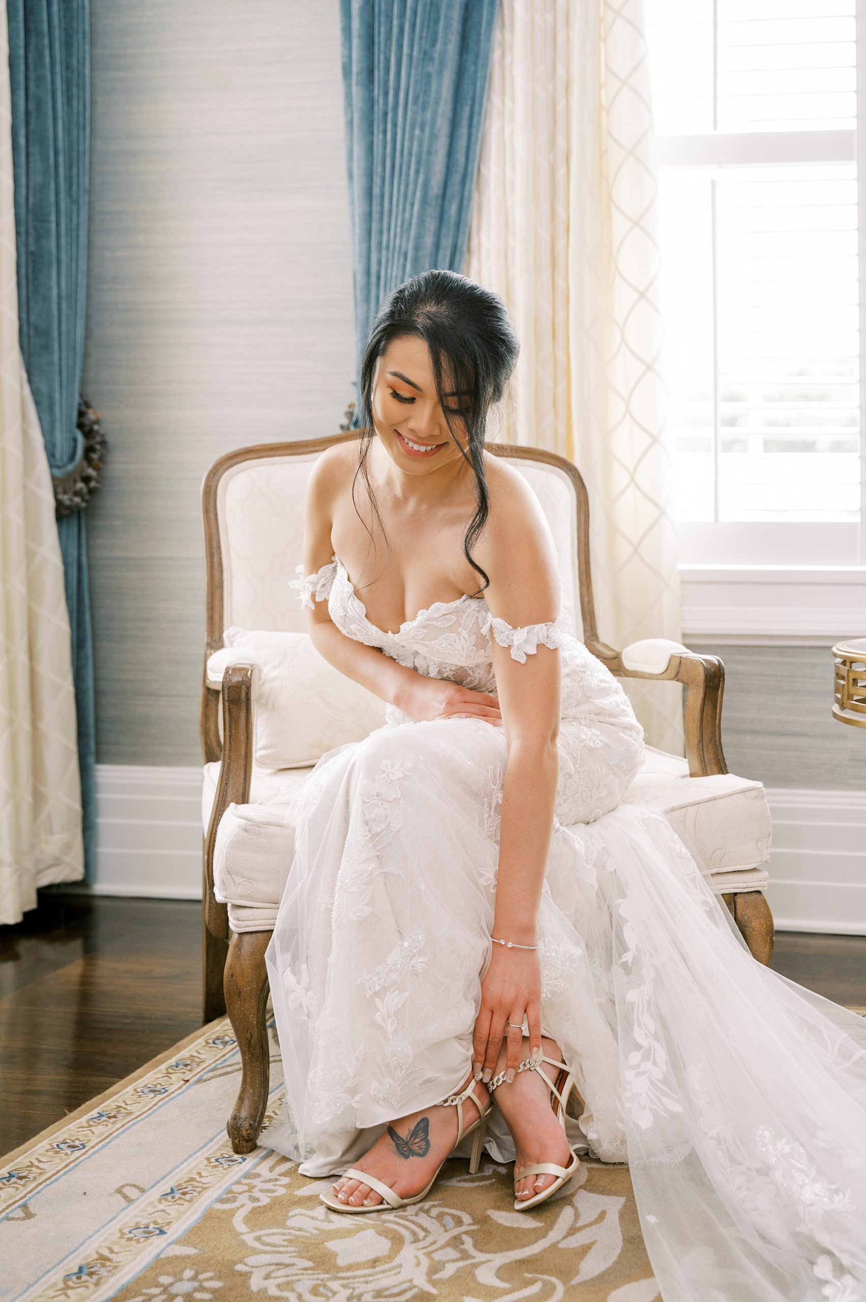 bride adjusts shoes sitting in bridal suite at Shadowbrook at Shrewsbury