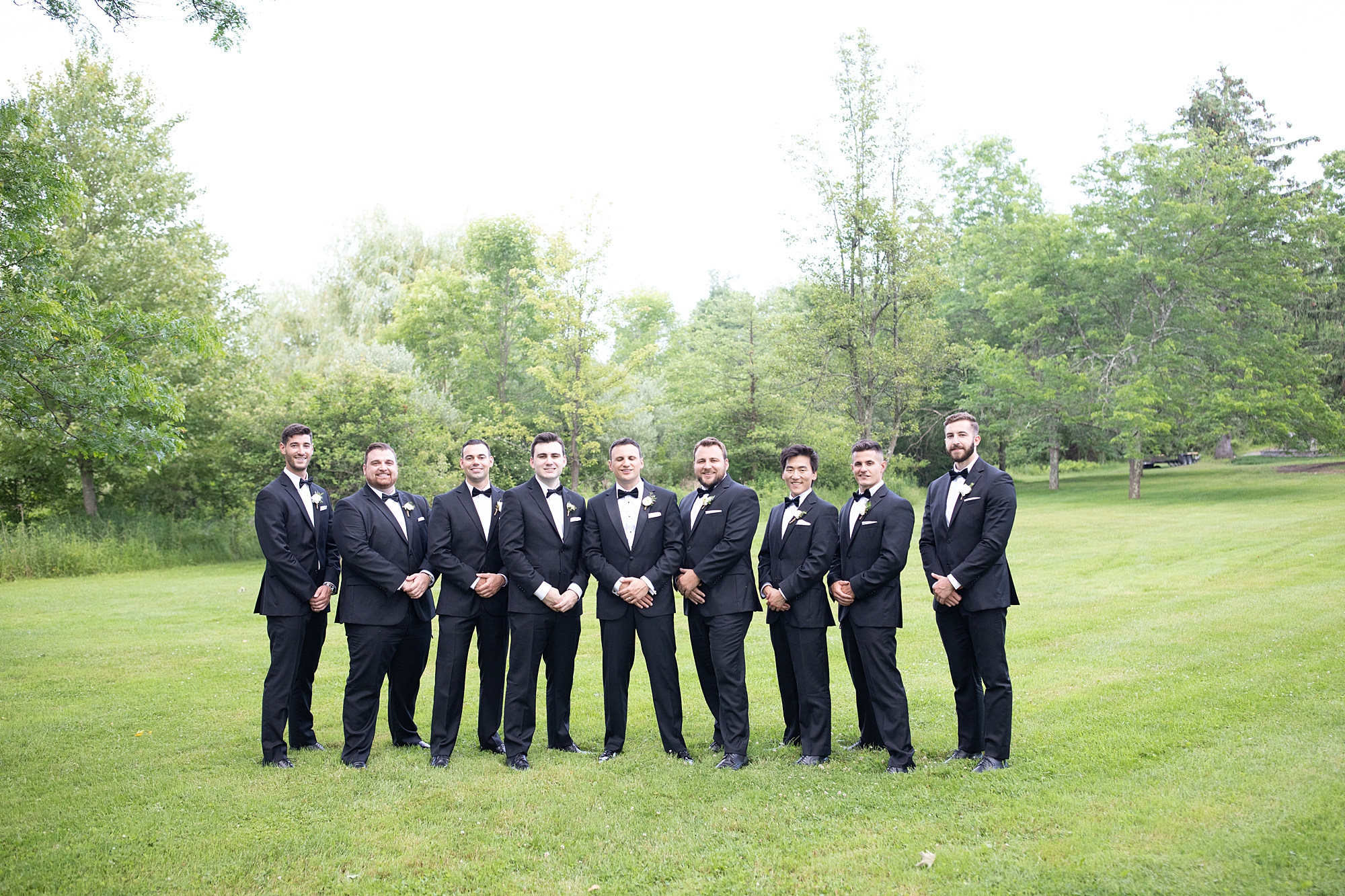groom stands with groomsmen in classic tuxes at Crossed Keys Estate