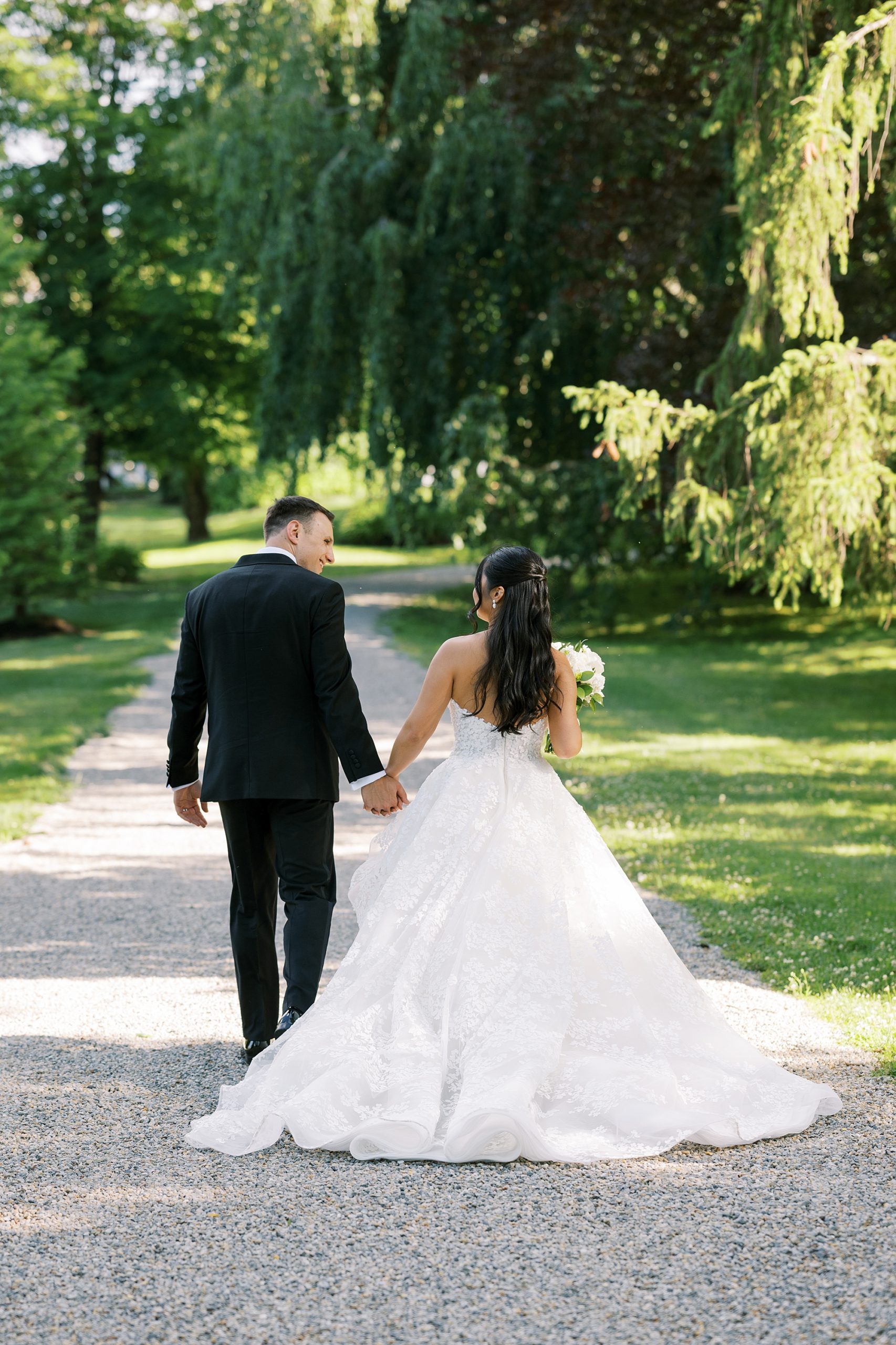 bride and groom hold hands walking through Crossed Keys Estate