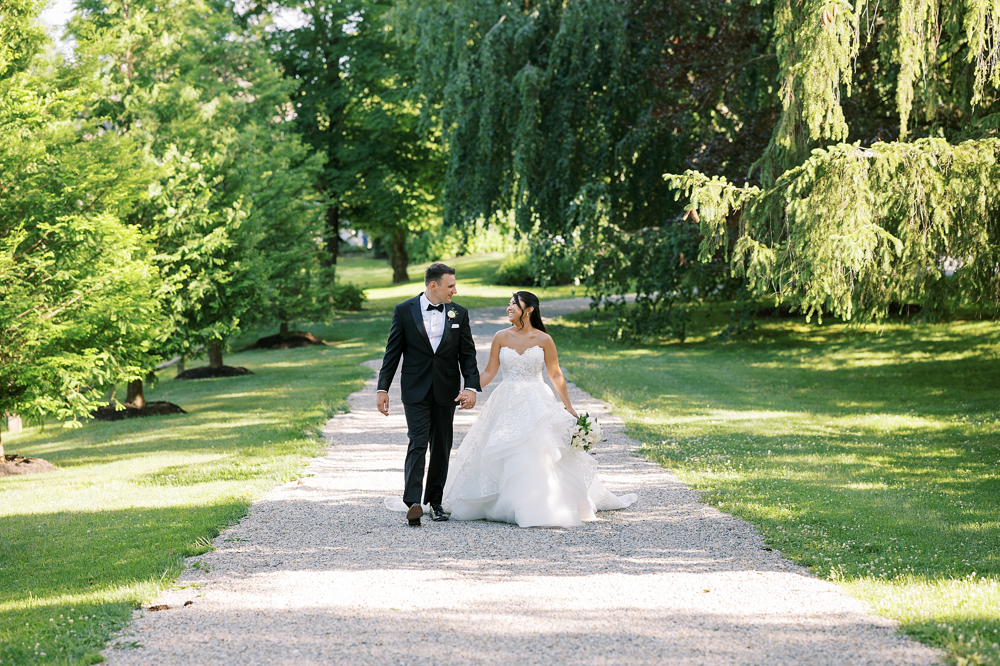 newlyweds hold hands walking on pathway in Crossed Keys Estate