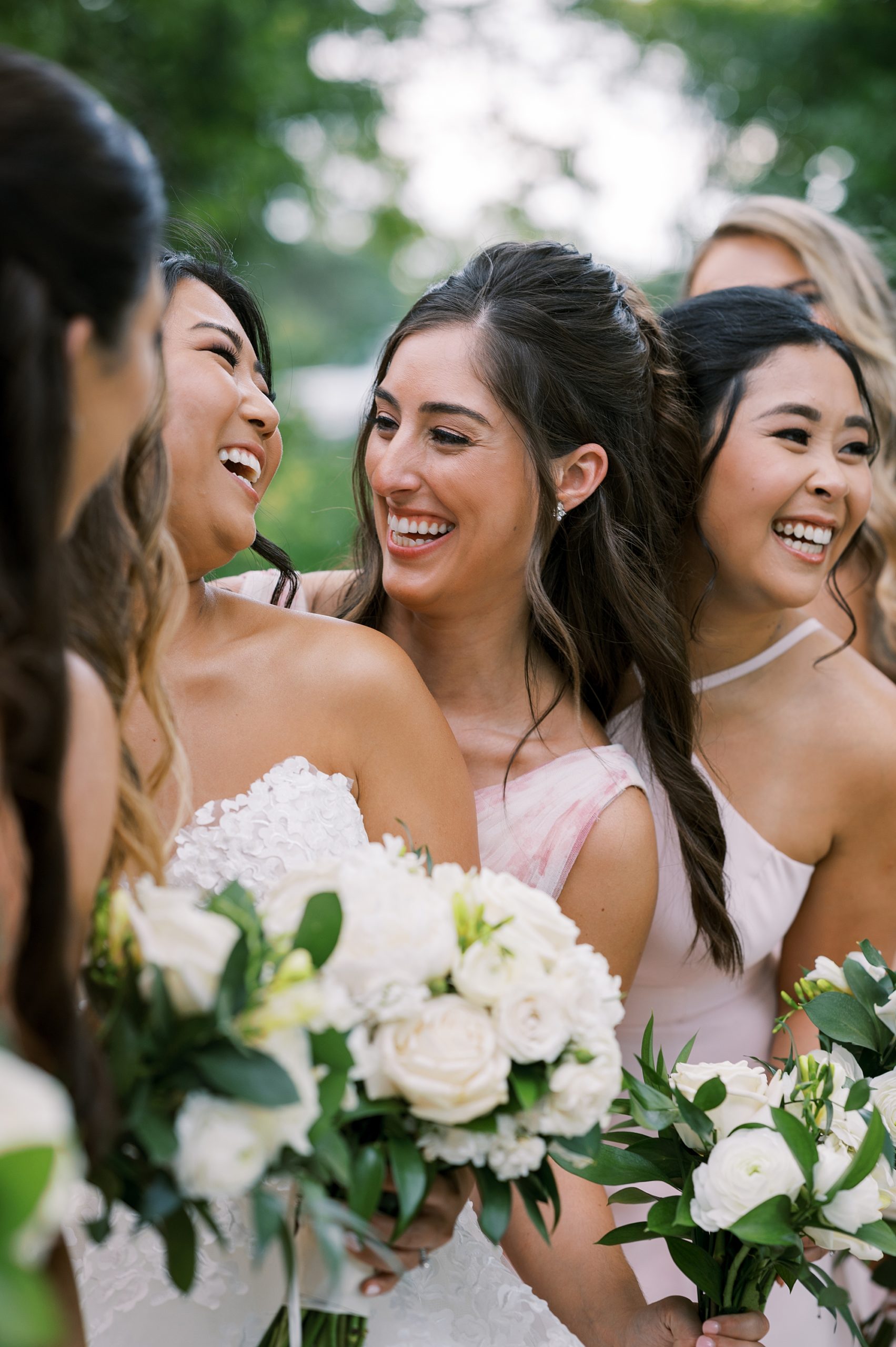 bridesmaids laugh with bride standing with summer bouquets 