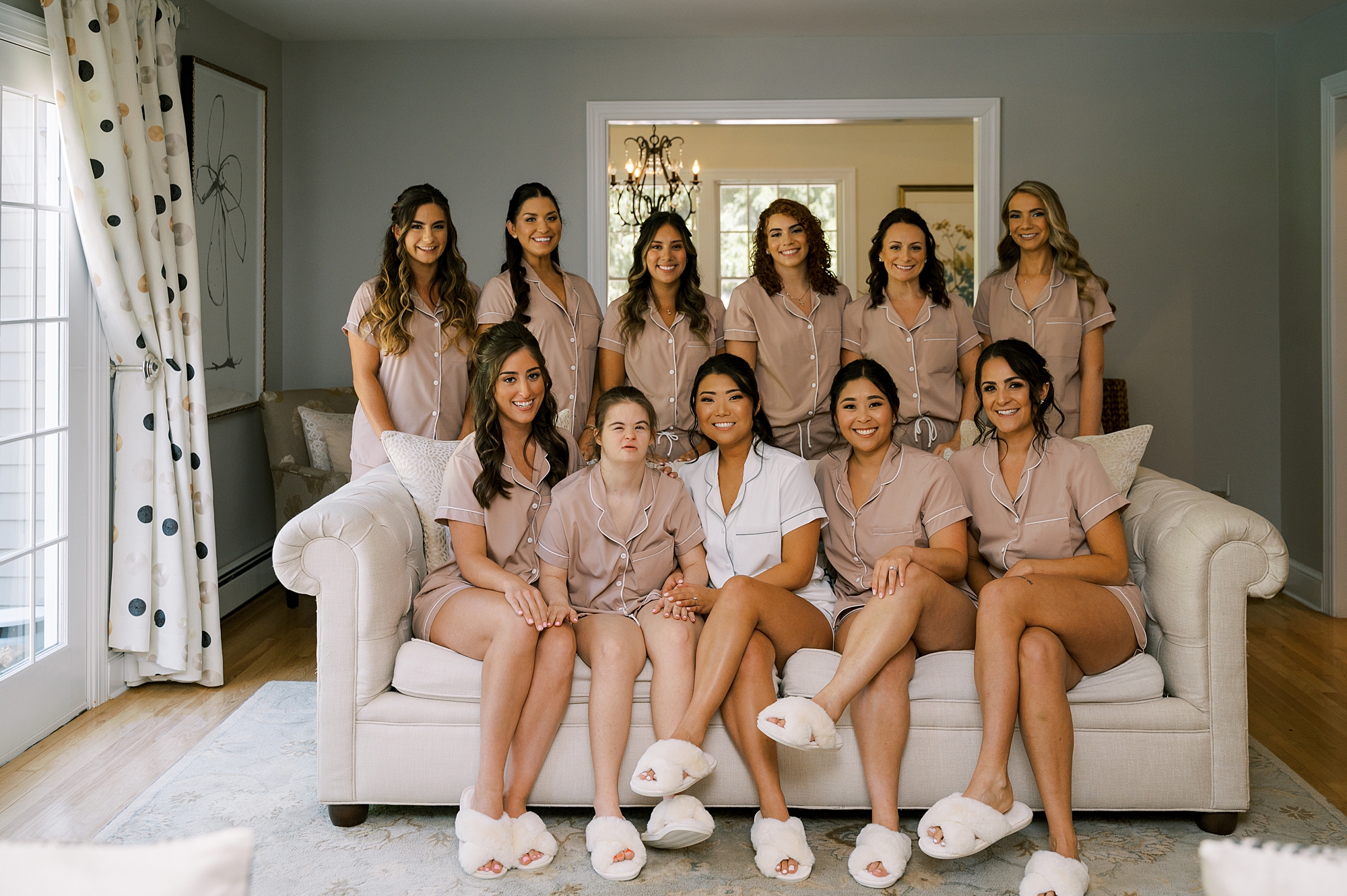 bride sits on couch with bridesmaids during Crossed Keys Estate wedding day prep 