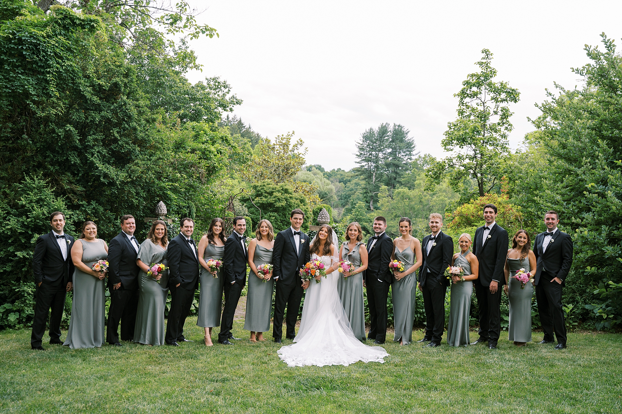 newlyweds stand with wedding party at Willowwood Arboretum