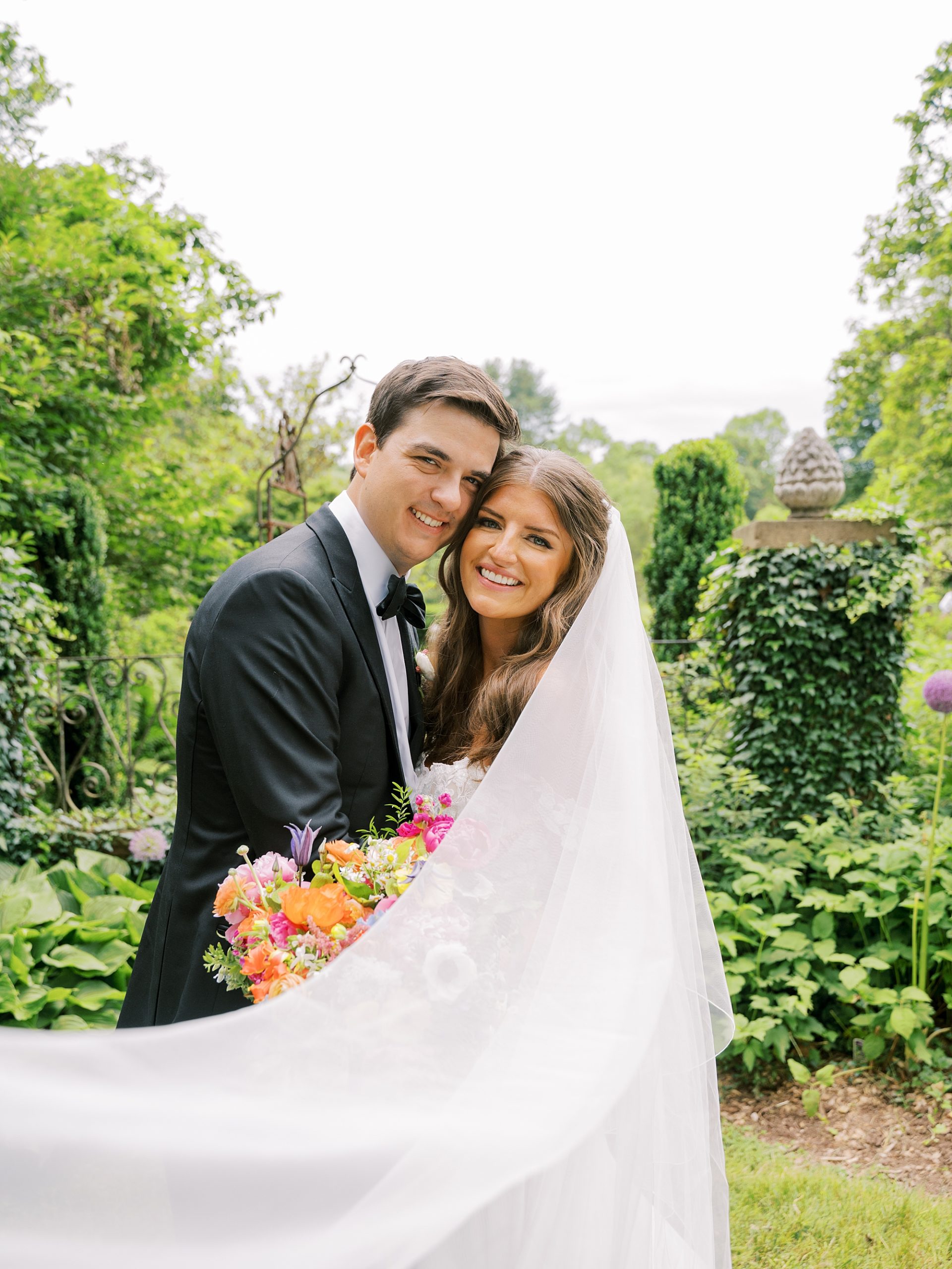 newlyweds lean heads together during Willowwood Arboretum wedding portraits