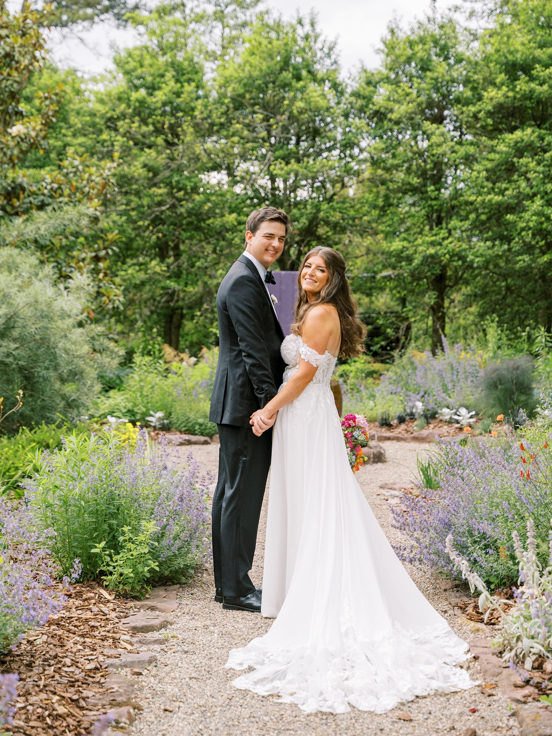 bride and groom hold hands among lavender at Willowwood Arboretum