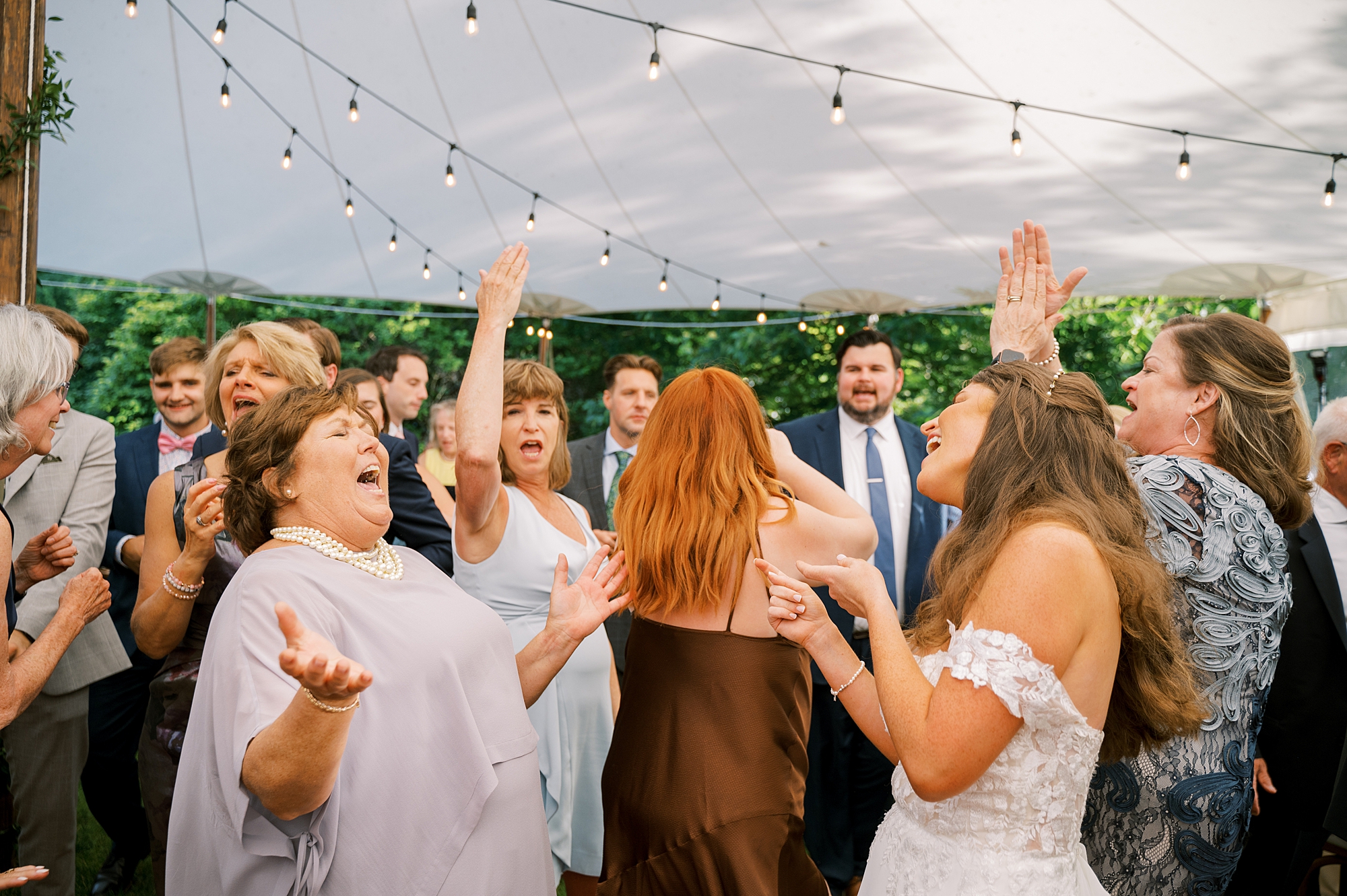 bride dances with family and friends under tent at Willowwood Arboretum