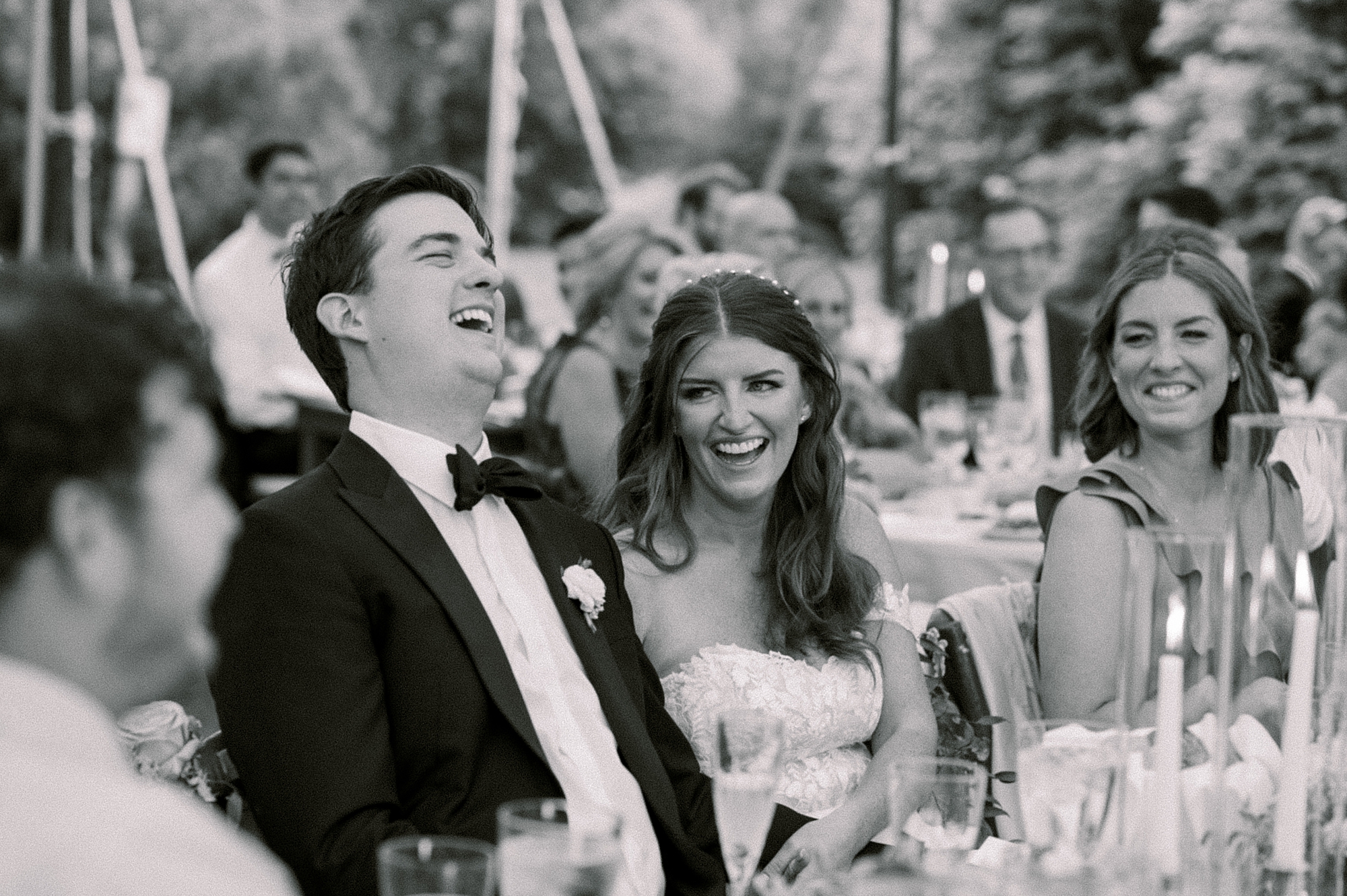 bride laughs with groom during tented wedding reception at Willowwood Arboretum