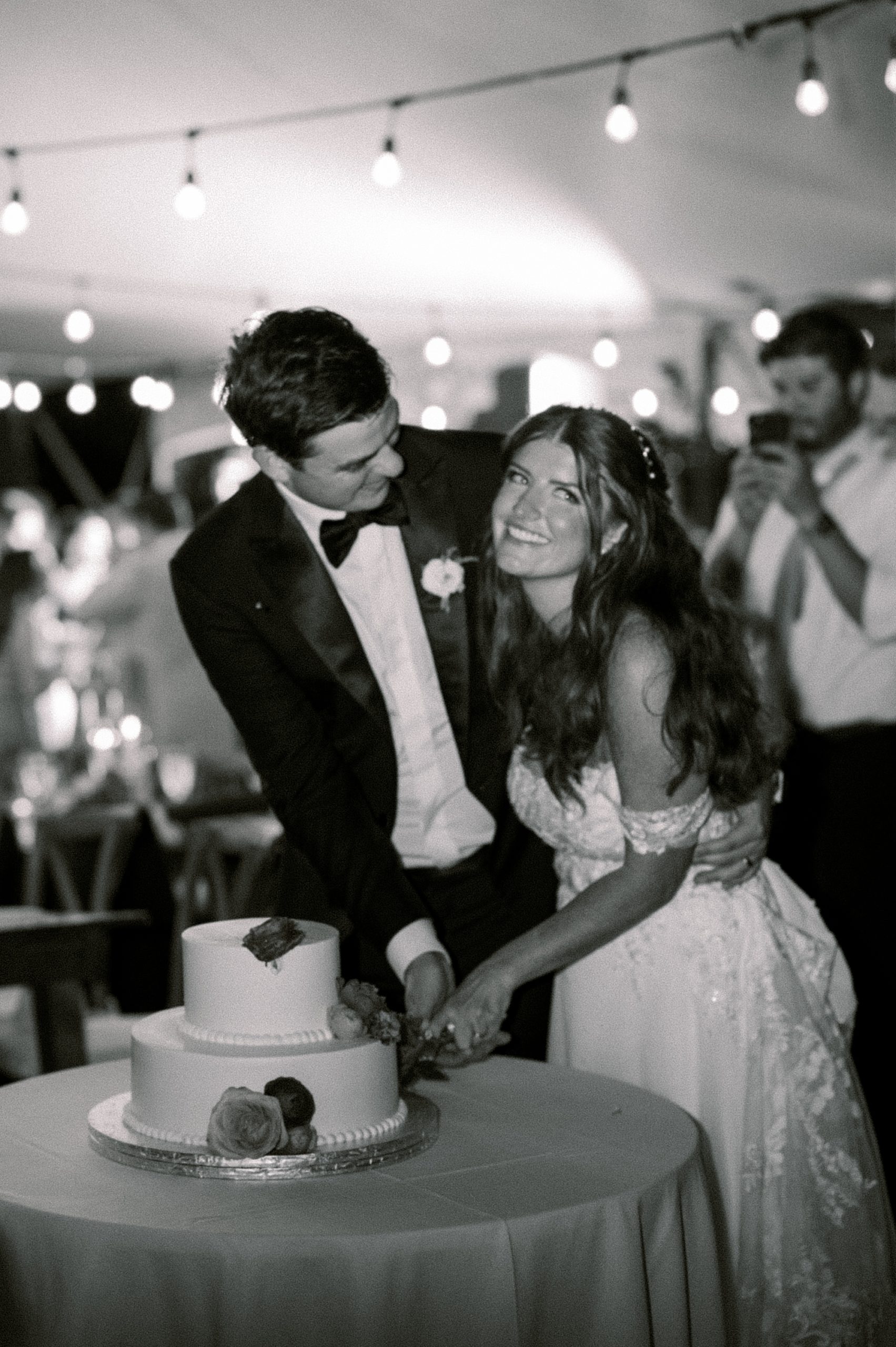 bright and groom cut wedding cake under tent at Willowwood Arboretum