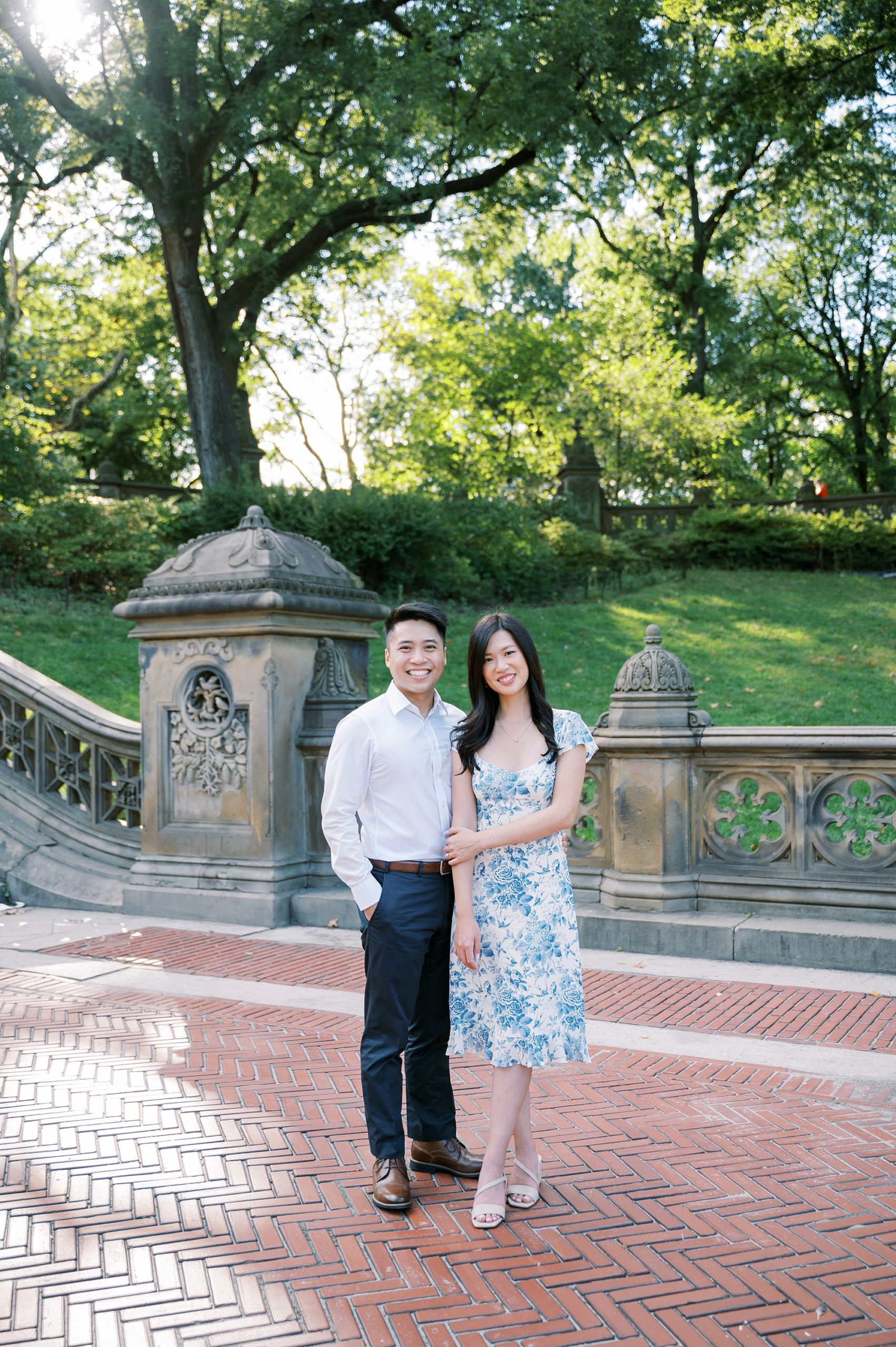 engaged couple stands side by side on brick patio in Central Park