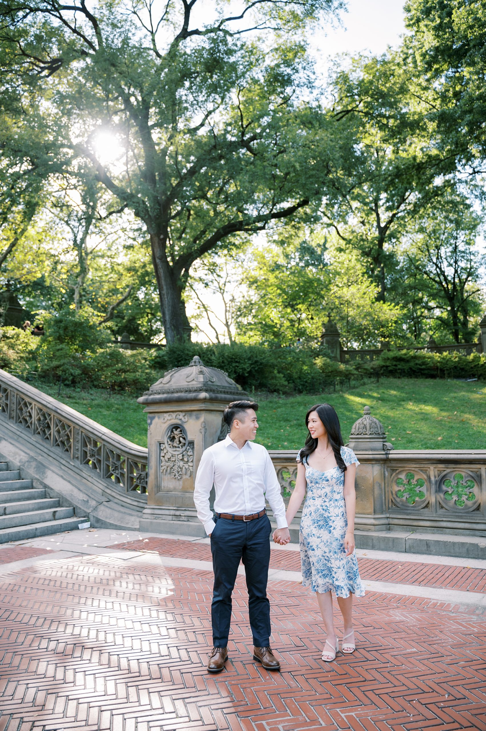 engaged couple holds hands walking through Central Park