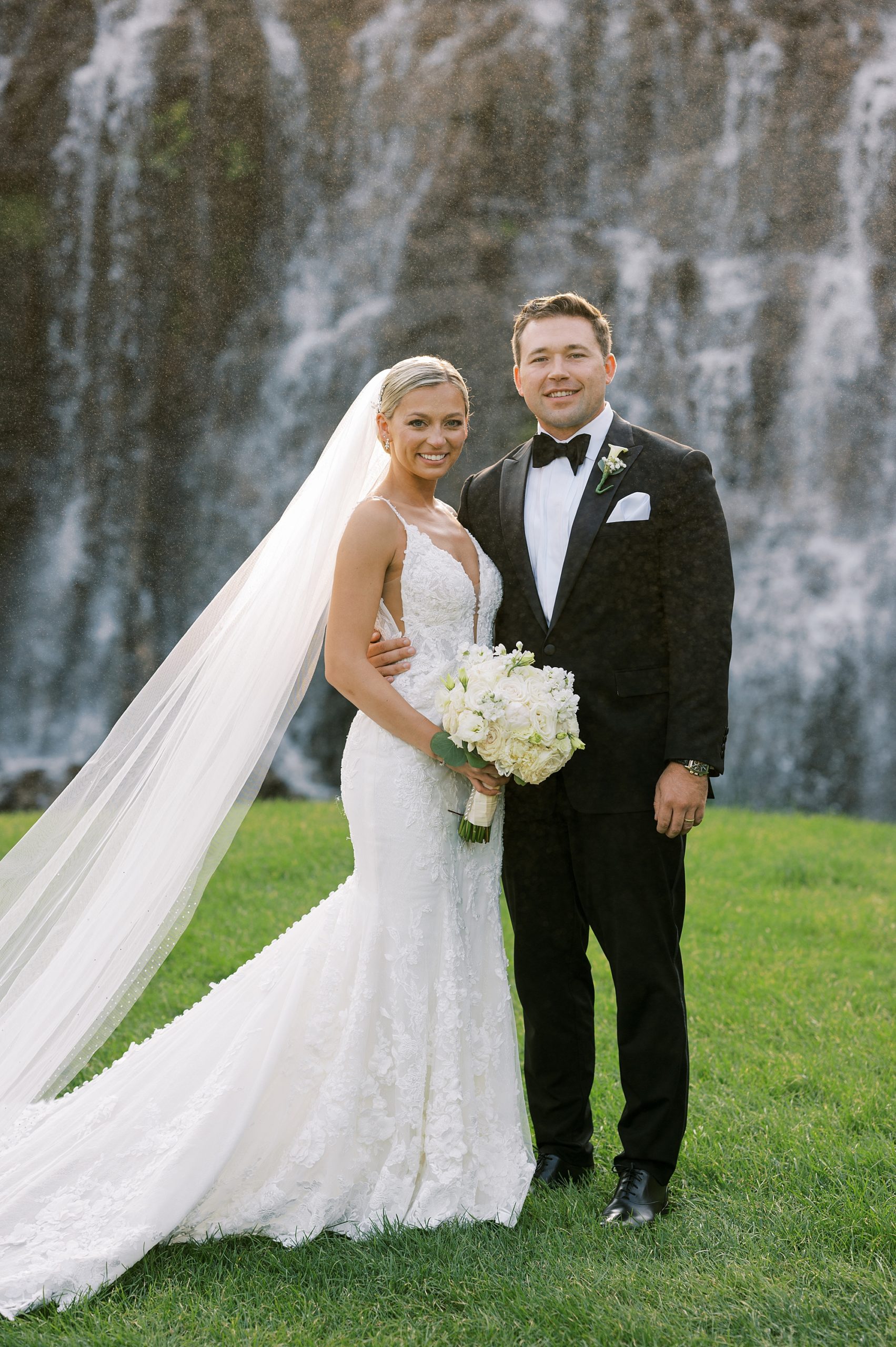 newlyweds stand together in front of waterfall at Trump National Golf Club Westchester