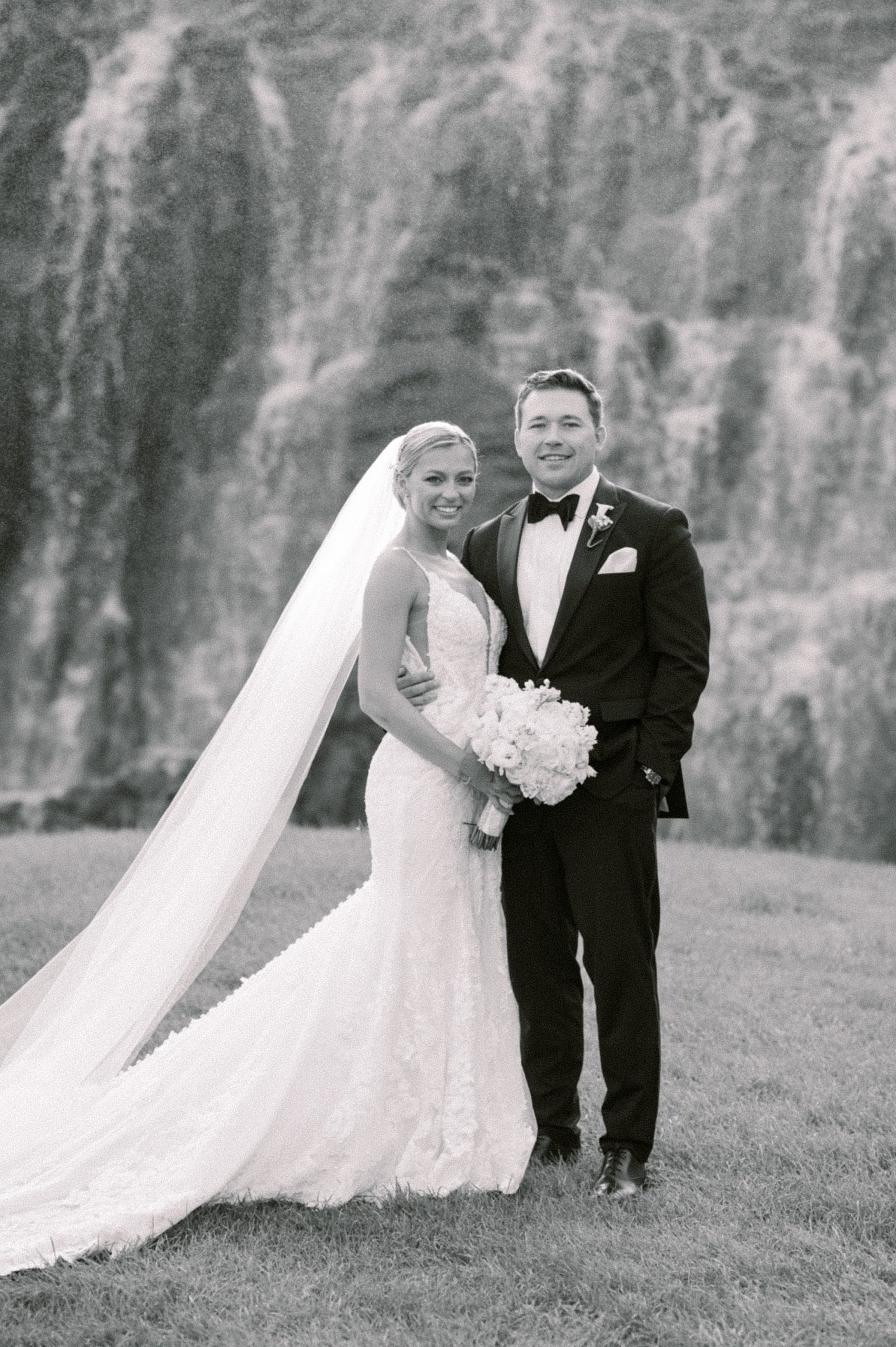 black and white portrait of bride and groom by waterfall 