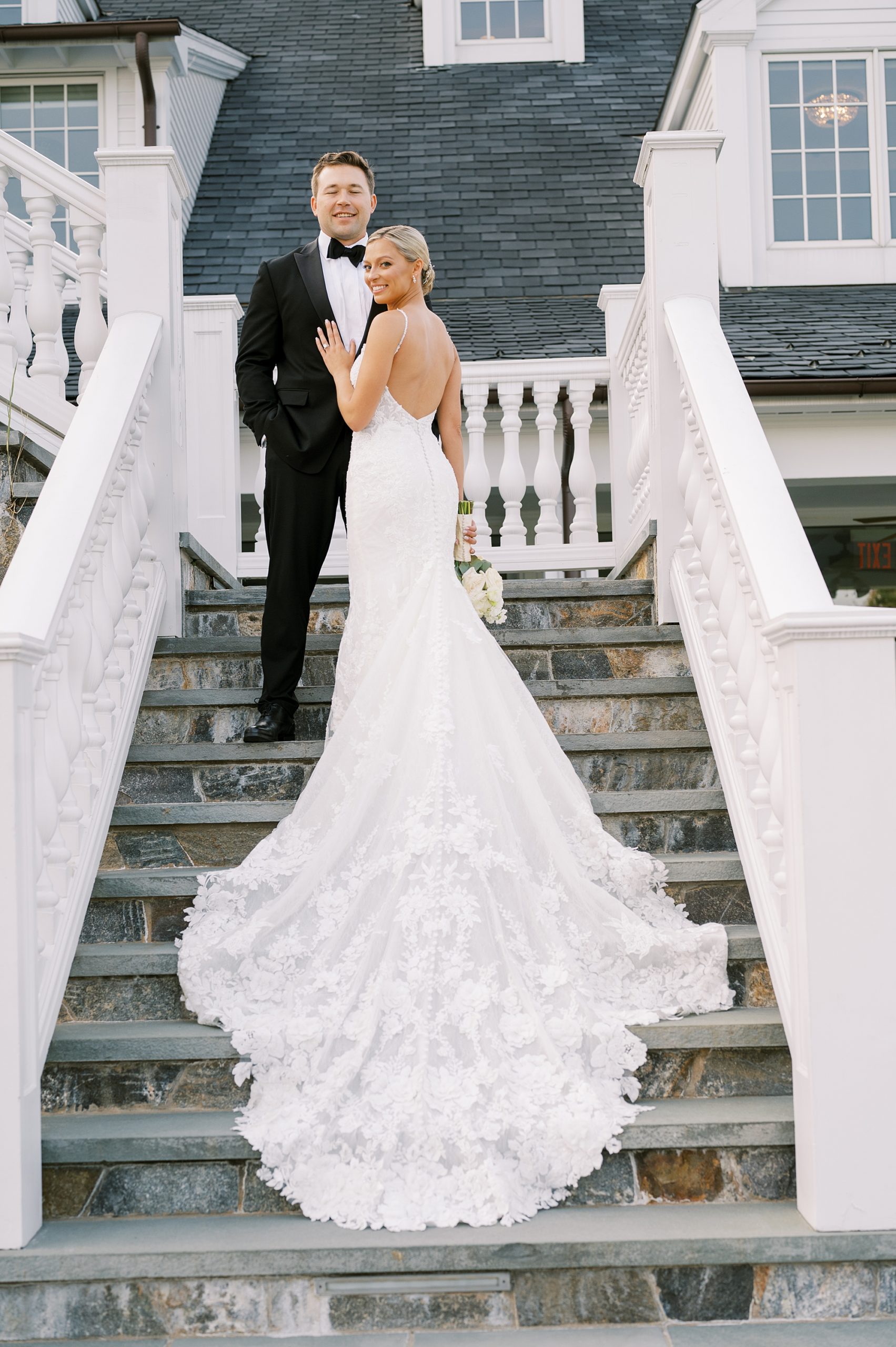 bride and groom stand on steps outside Trump National Golf Club Westchester