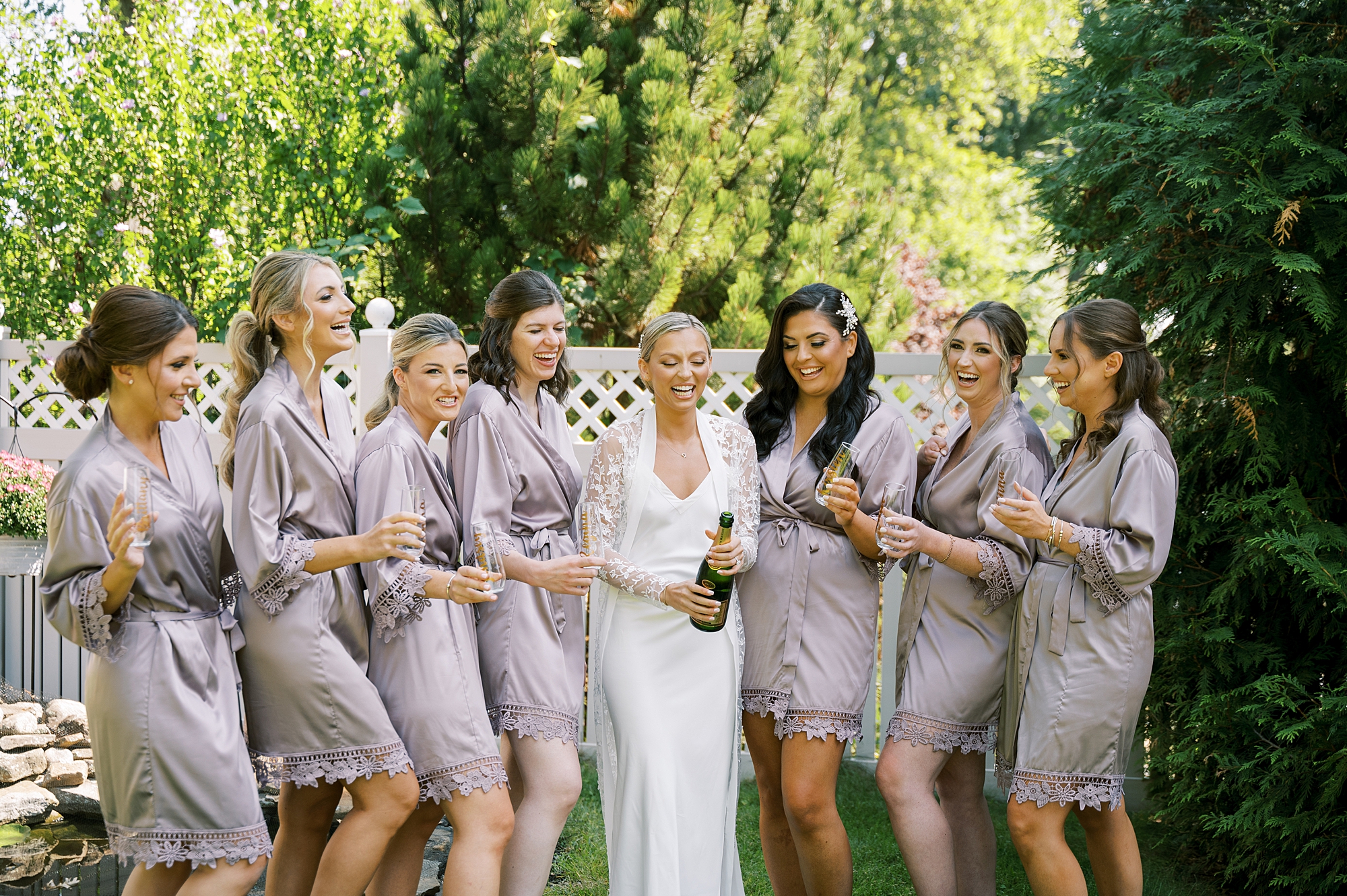 bride pops champagne with bridesmaids in matching purple pajamas 