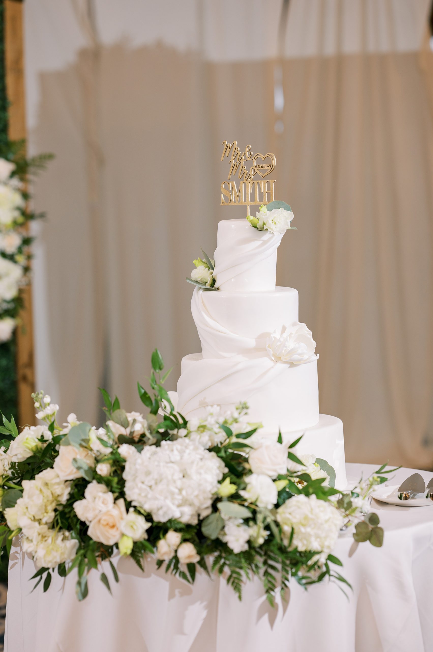 classic tiered white wedding cake with custom gold cake topper