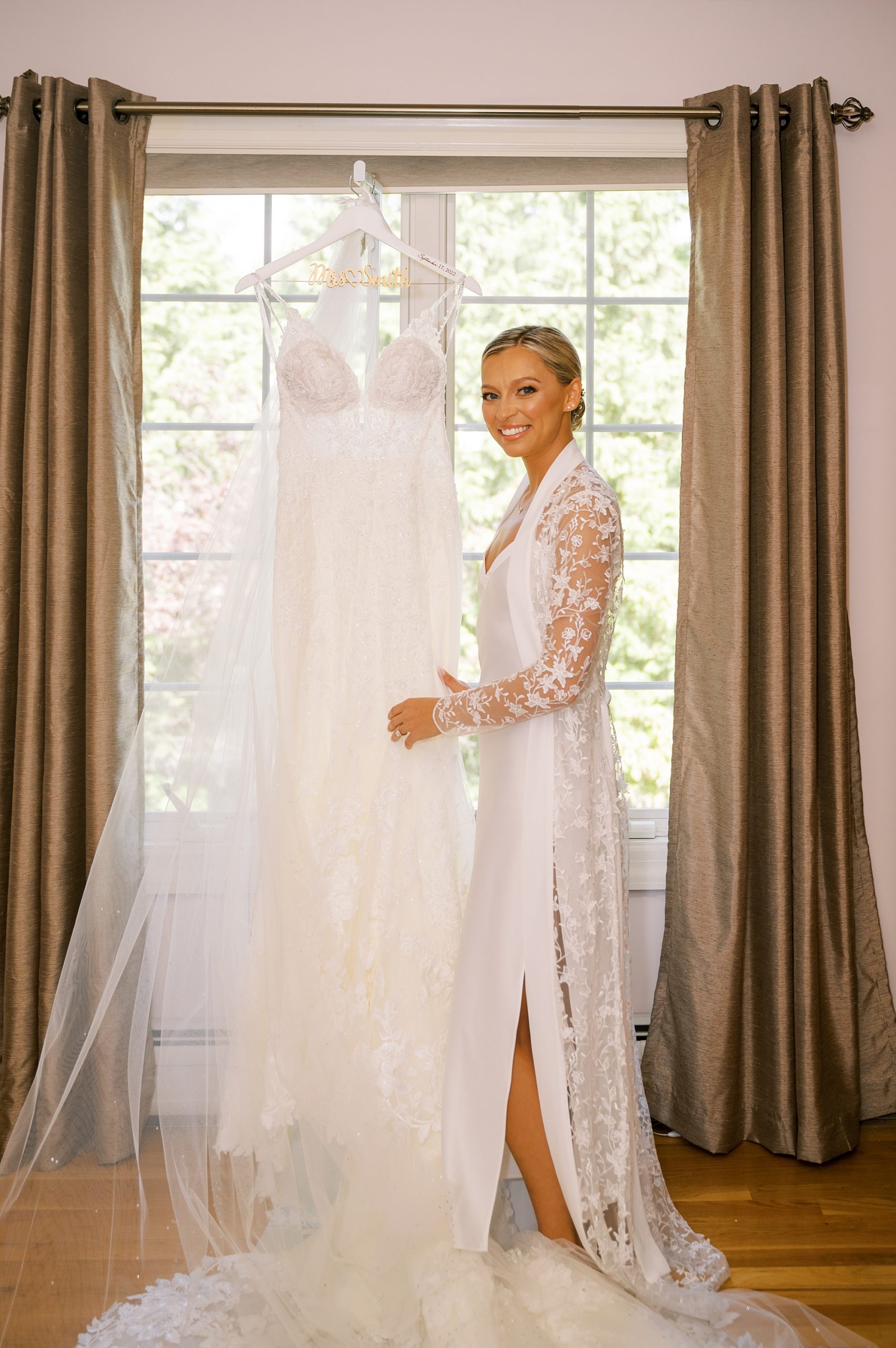 bride smiles next to wedding gown with lace bodice 