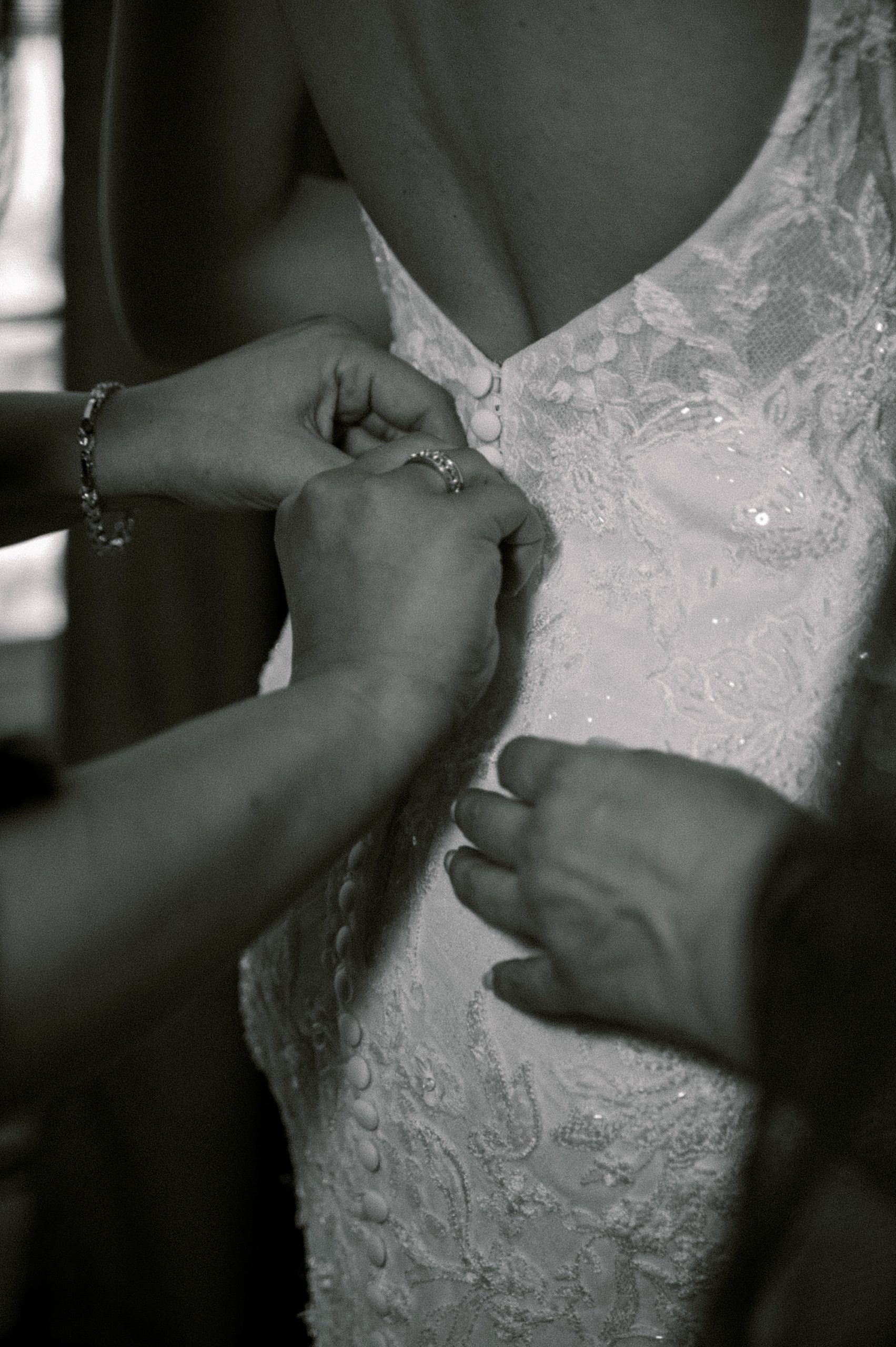 women help bride into wedding gown 