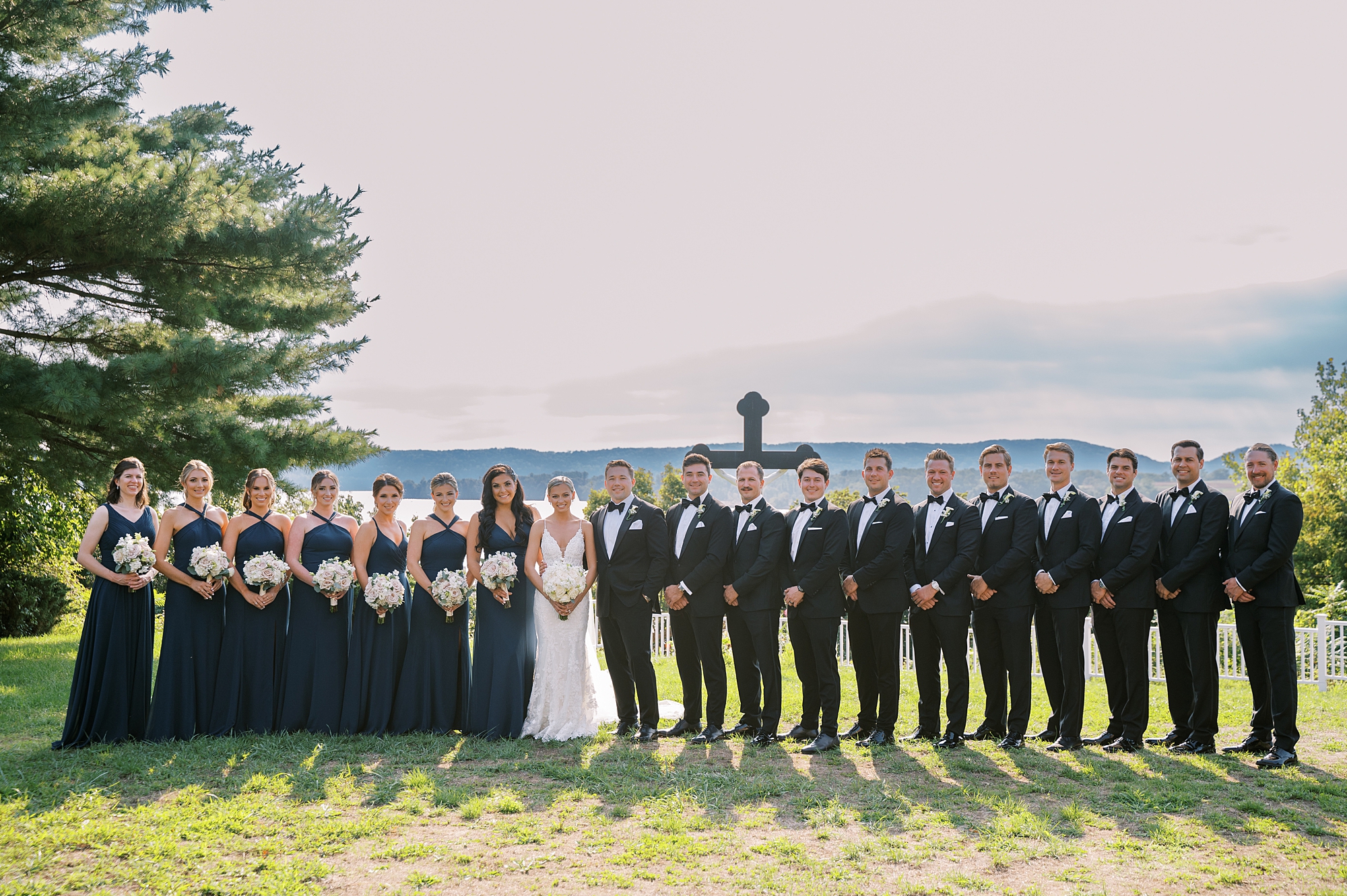 bride and groom pose with wedding party by cross