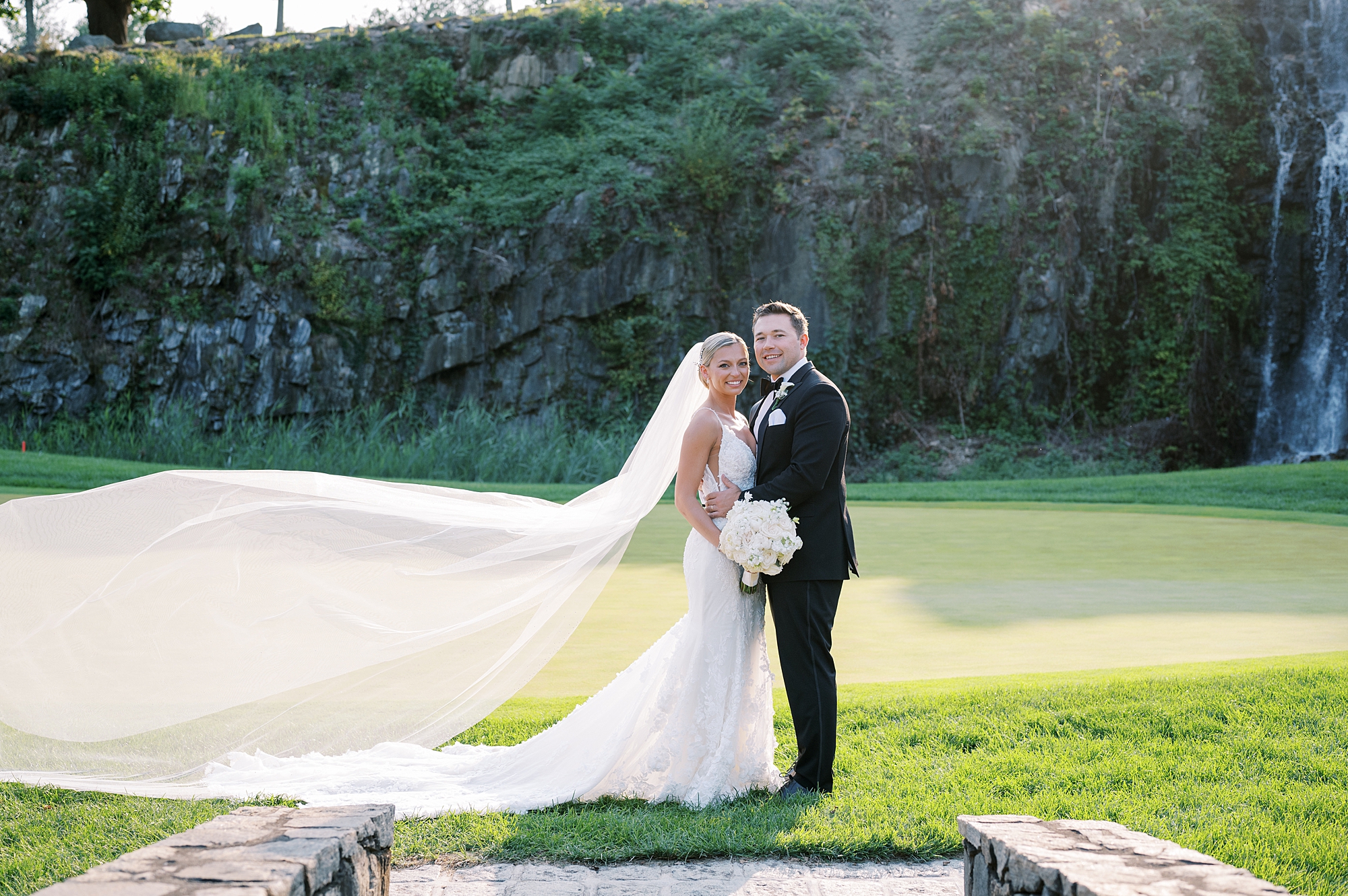 newlyweds pose by mossy wall at  Trump National Golf Club Westchester
