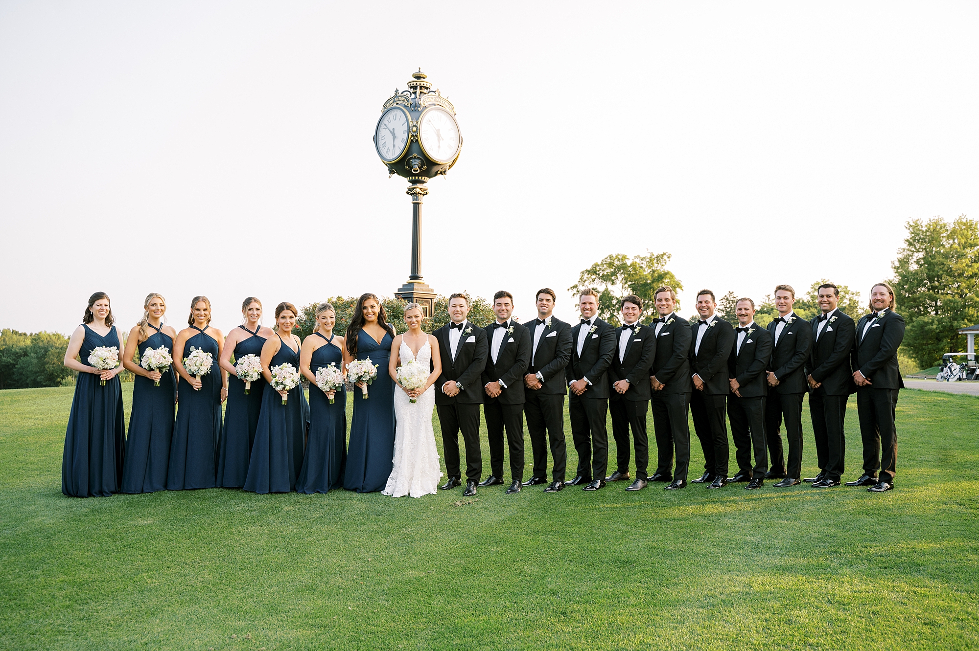 bride and groom stand with wedding party in navy blue and black at Trump National Golf Club Westchester