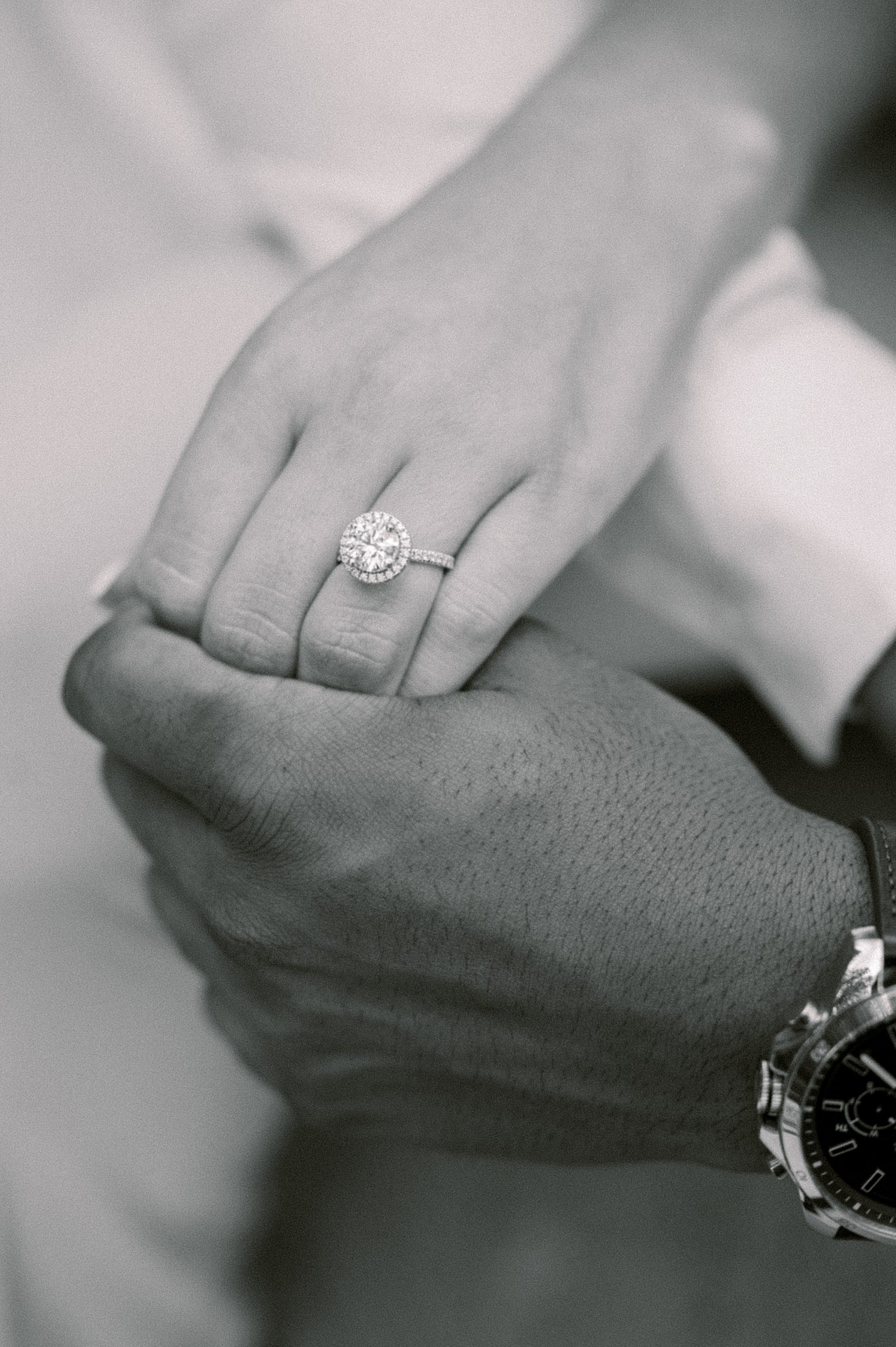 man holds fiancee's hand showing off engagement ring