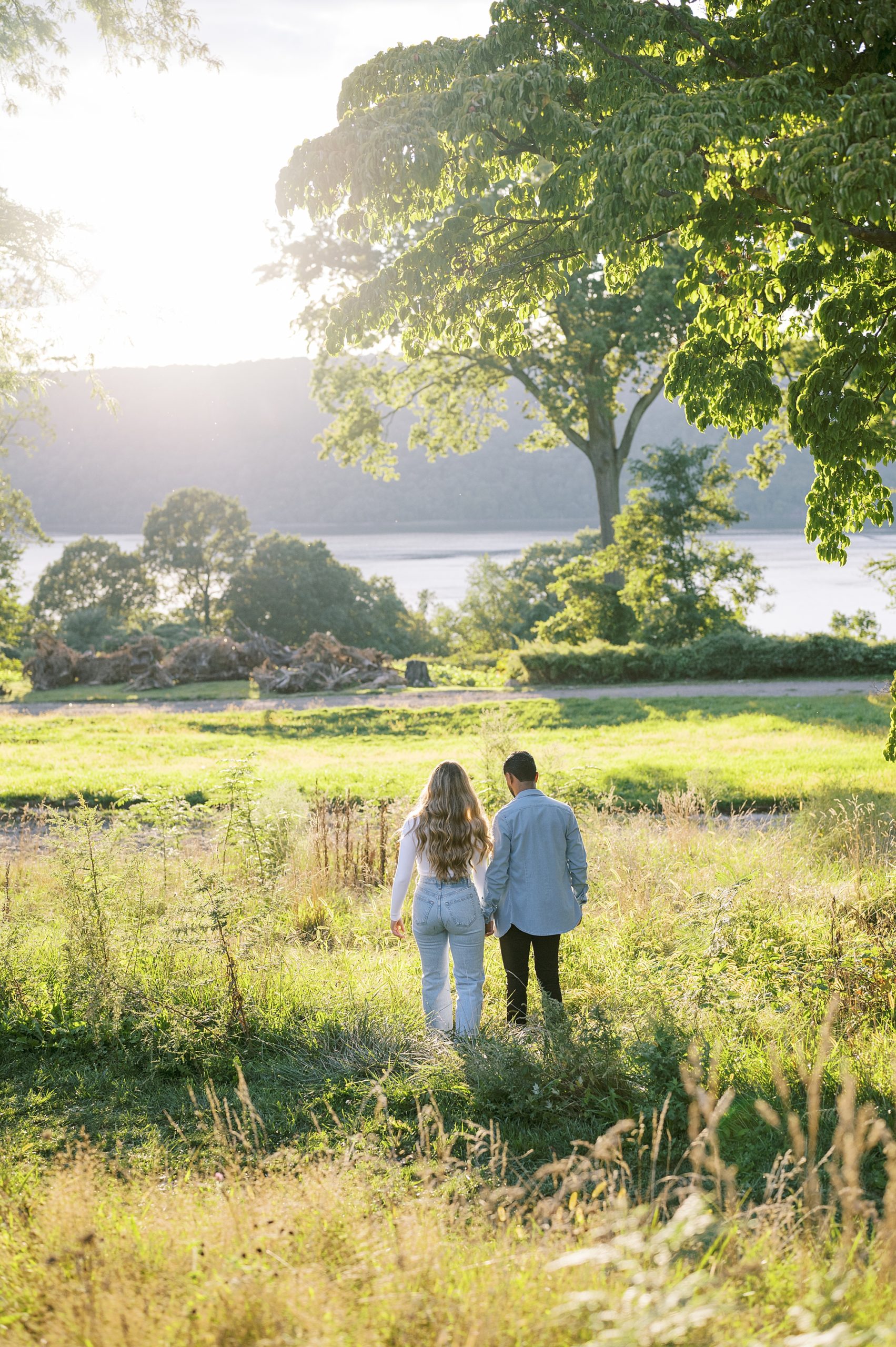 engaged couple walks through field at sunset in Yonkers NY