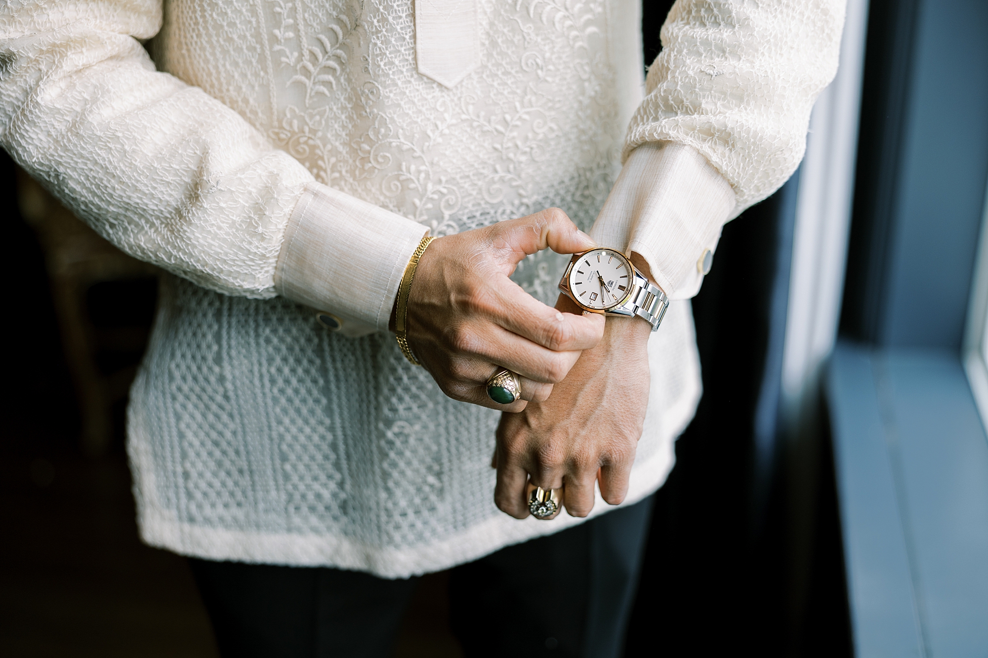 groom adjusts watch in front of linen shirt