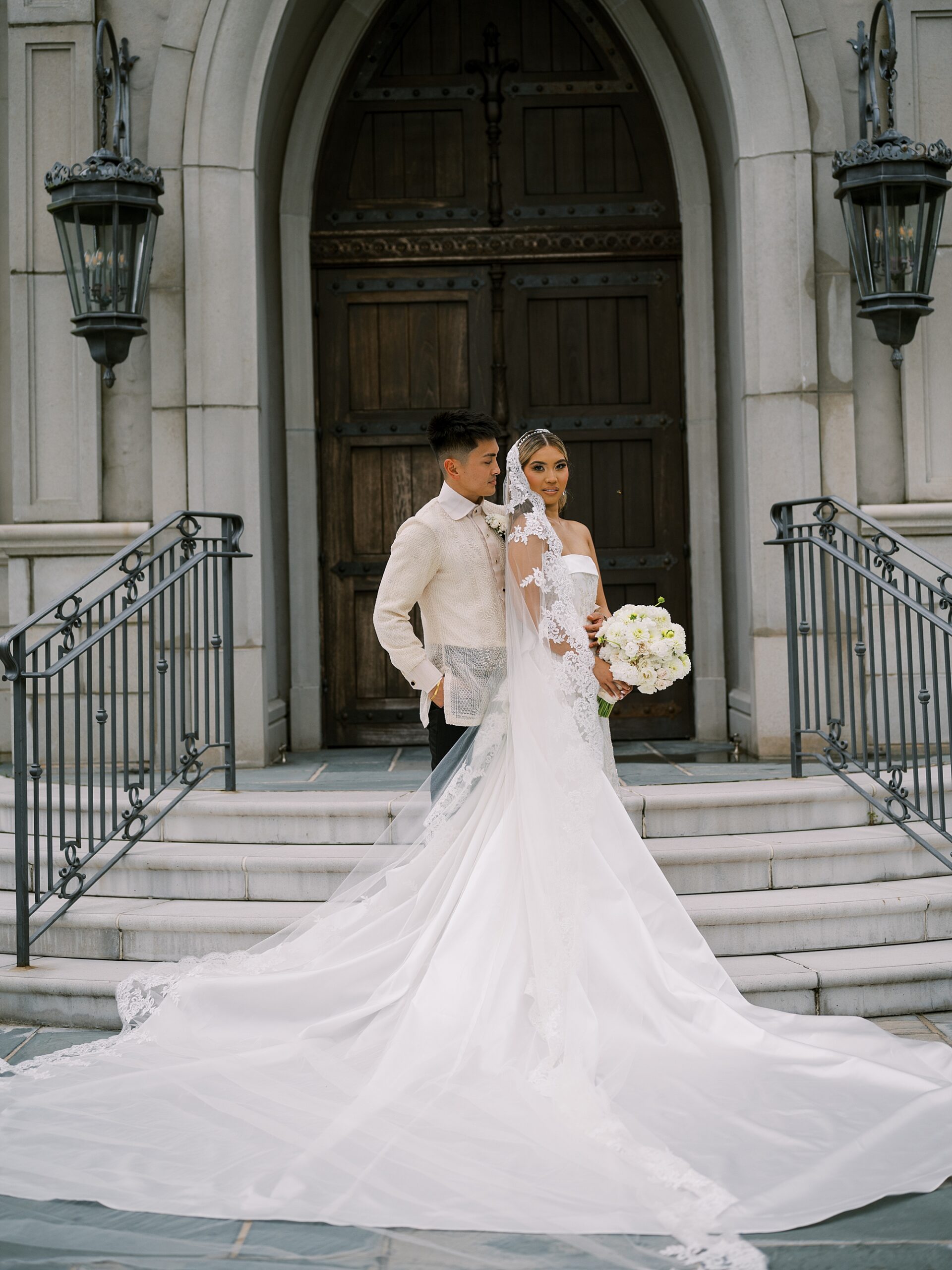 groom stands behind bride holding her hip in front of wooden chapel doors at Park Chateau Estate