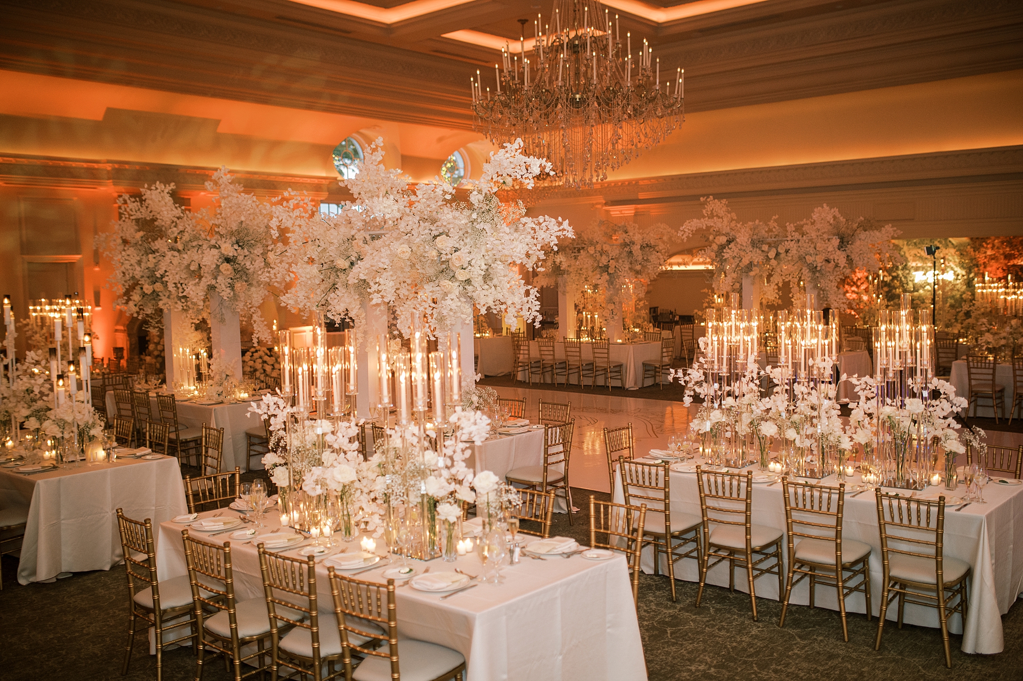 wedding reception with tall floral centerpieces with feathers inside Park Chateau Estate