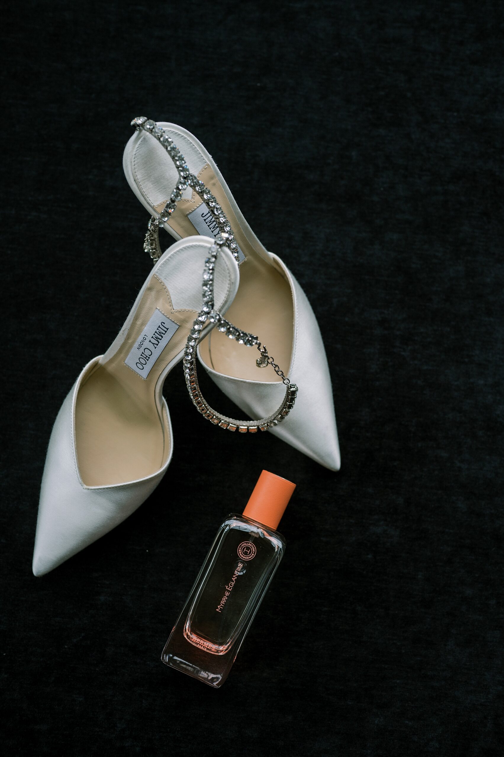 bride's white shoes with red lipstick on black backdrop