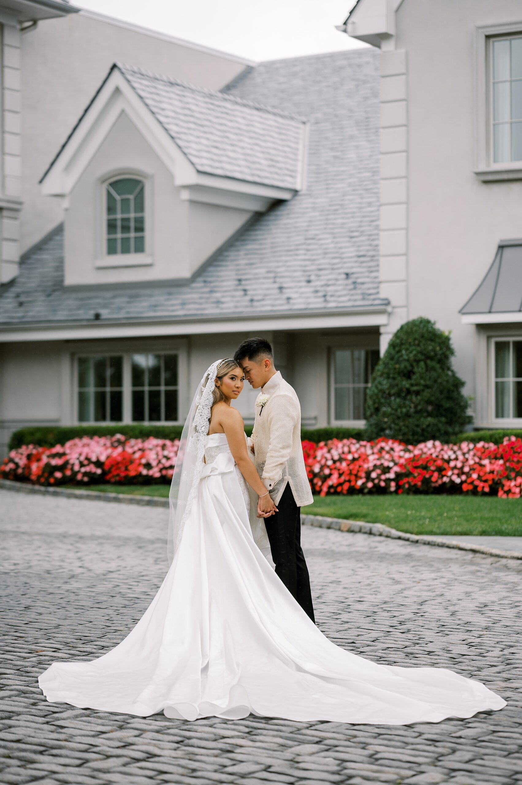 bride and groom hug on walkway outside Park Chateau Estate leaning heads together 