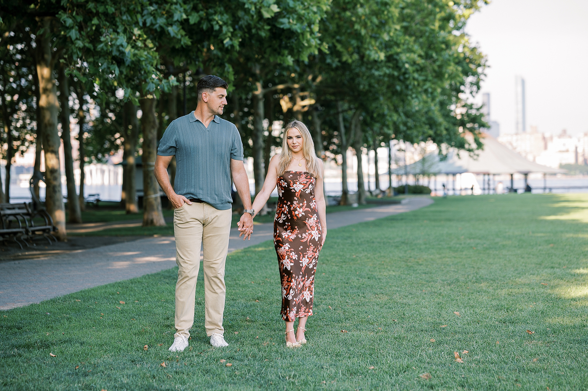 stylish engaged couple holds hands walking across lawn at Lackawanna Park