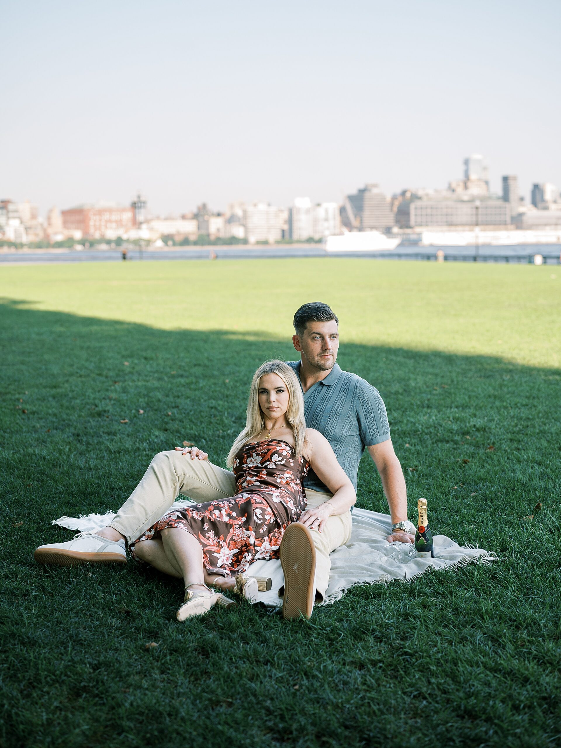 engaged couple sits on white picnic blanket at Lackawanna Park