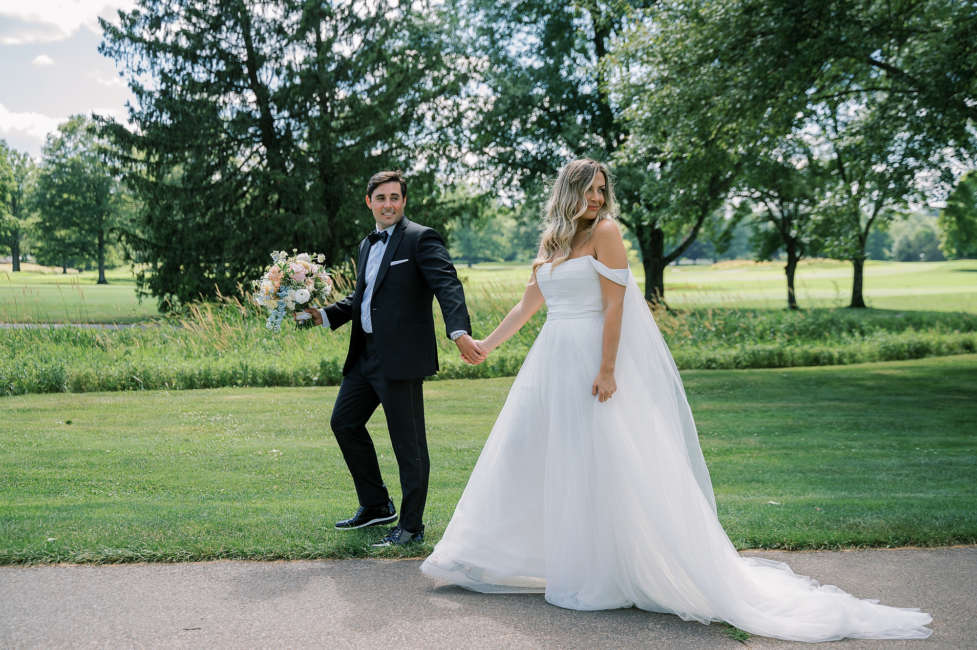 bride and groom hold hands walking on brick pathway at Fiddler's Elbow Country Club