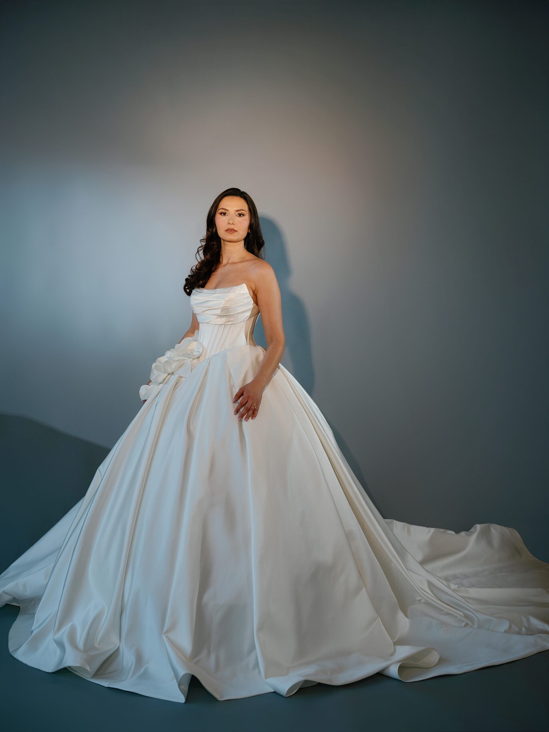 woman stands in strapless wedding gown inside Qendresa Bridal