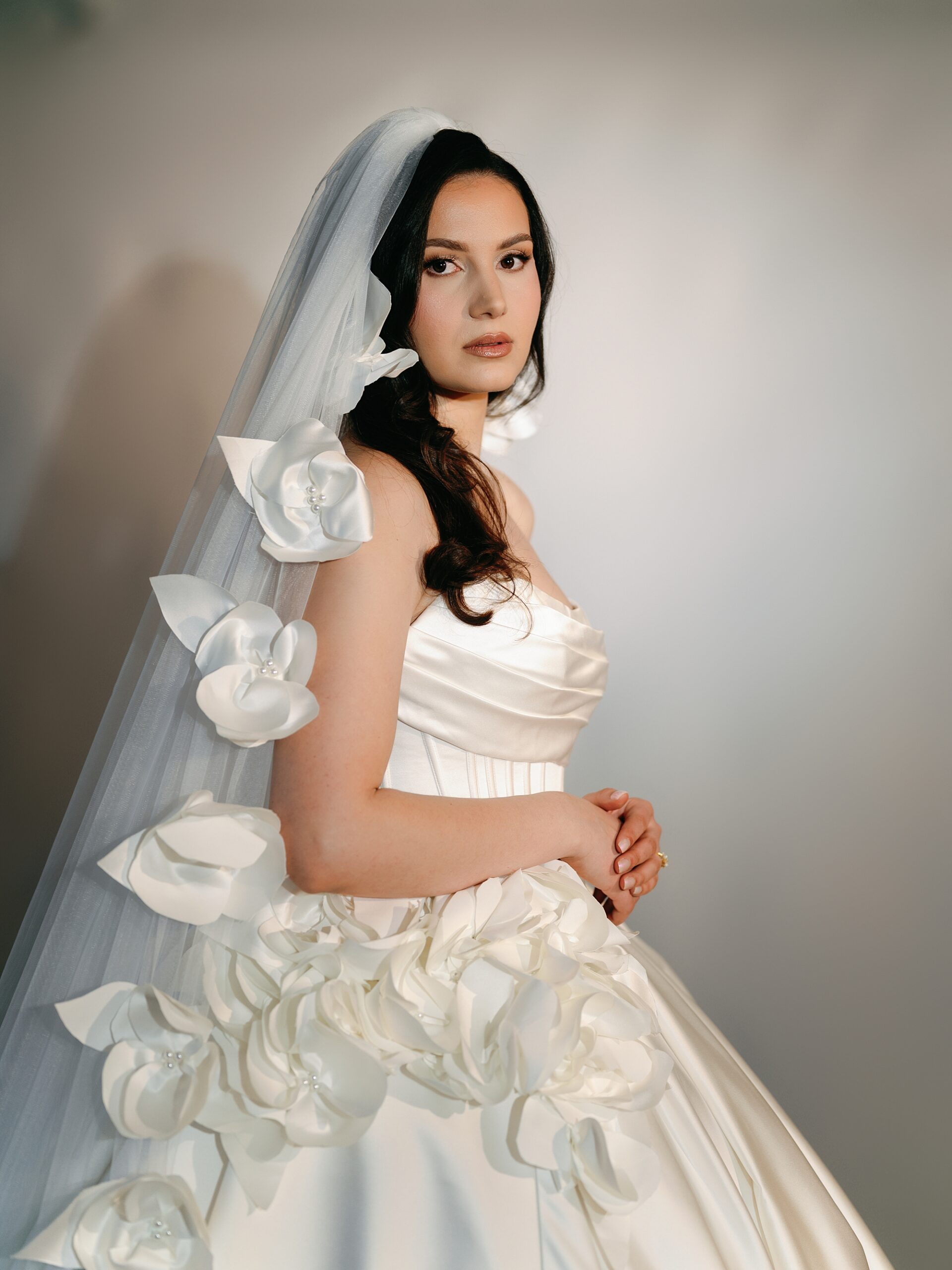 woman poses in wedding gown with flowers down veil and on gown