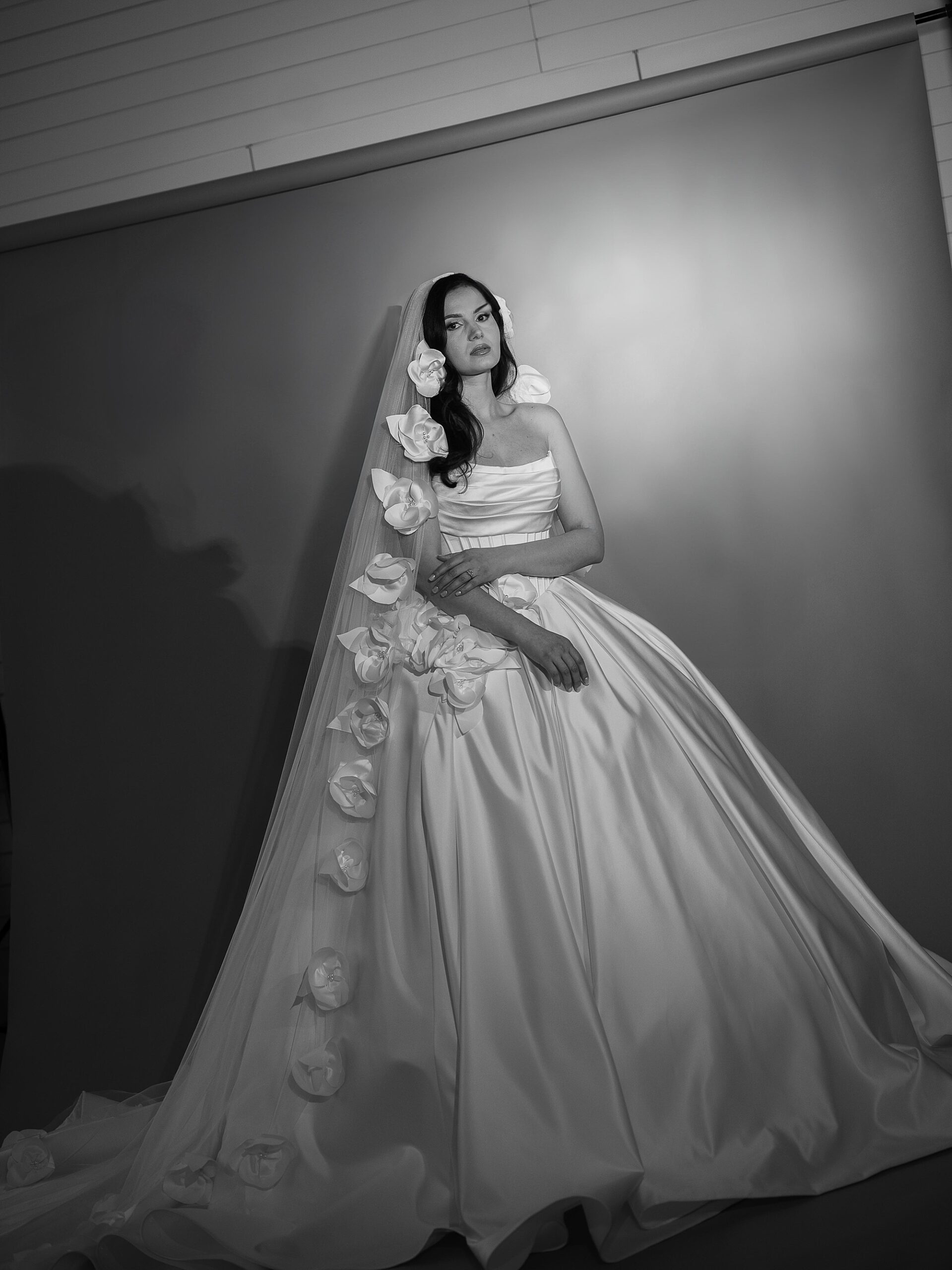 black and white dramatic portrait of bride standing in satin wedding gown