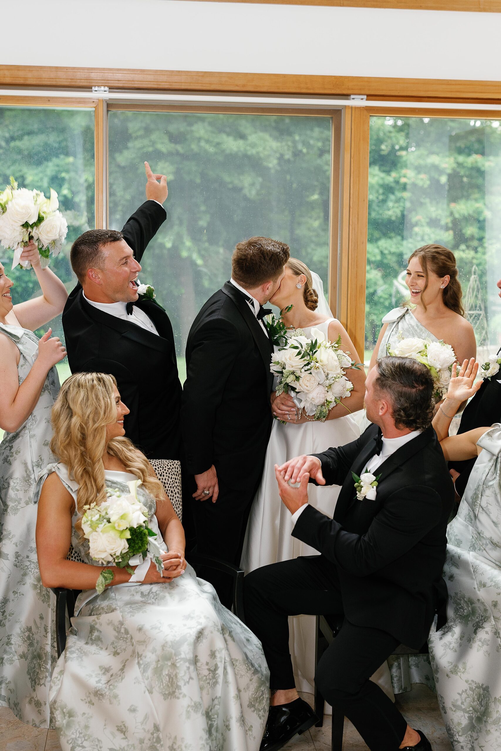 bride and groom kiss while wedding party cheers them on