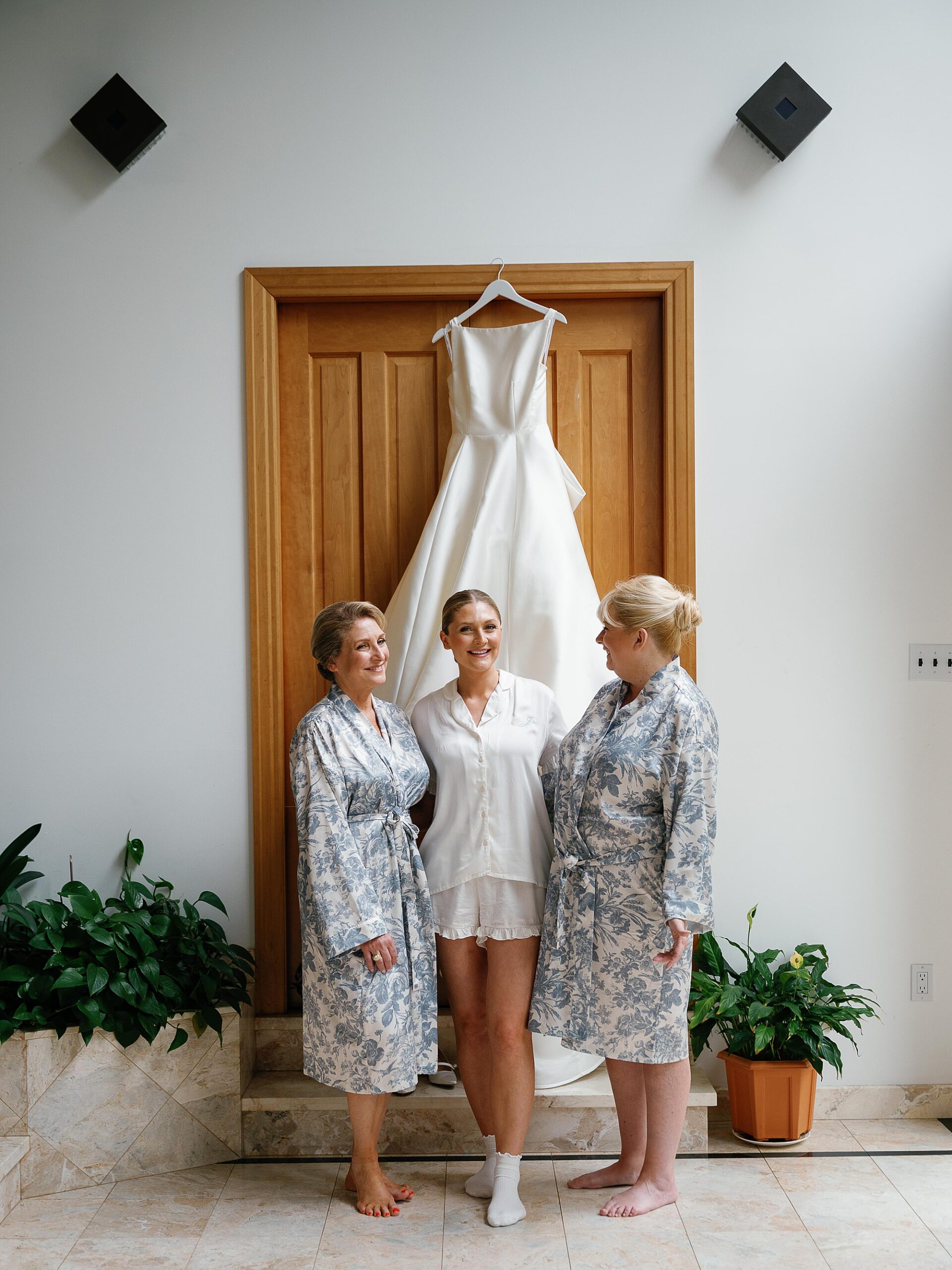 bride poses in front of wedding gown with family members