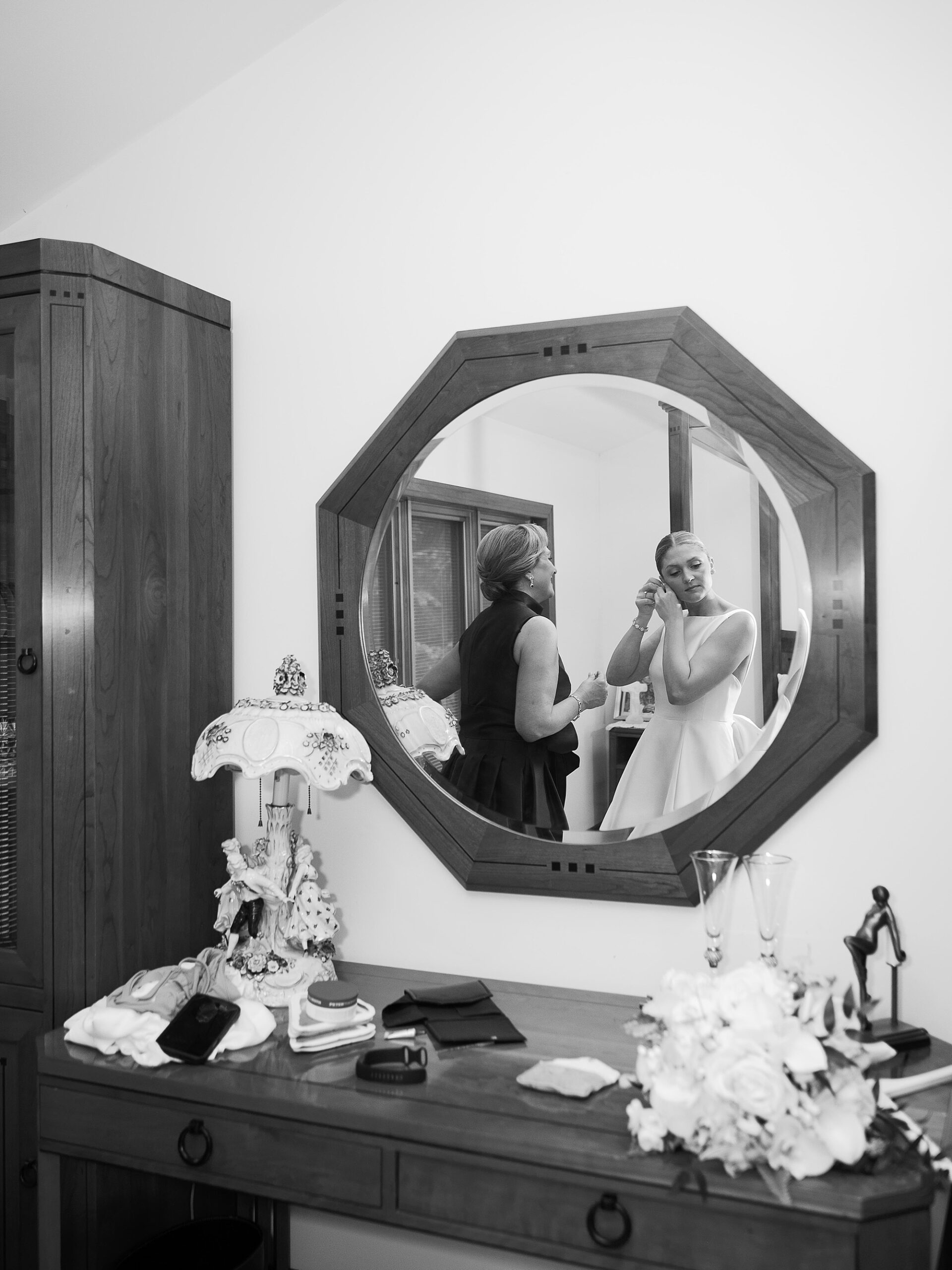 reflection of bride preparing with family in small mirror of family home