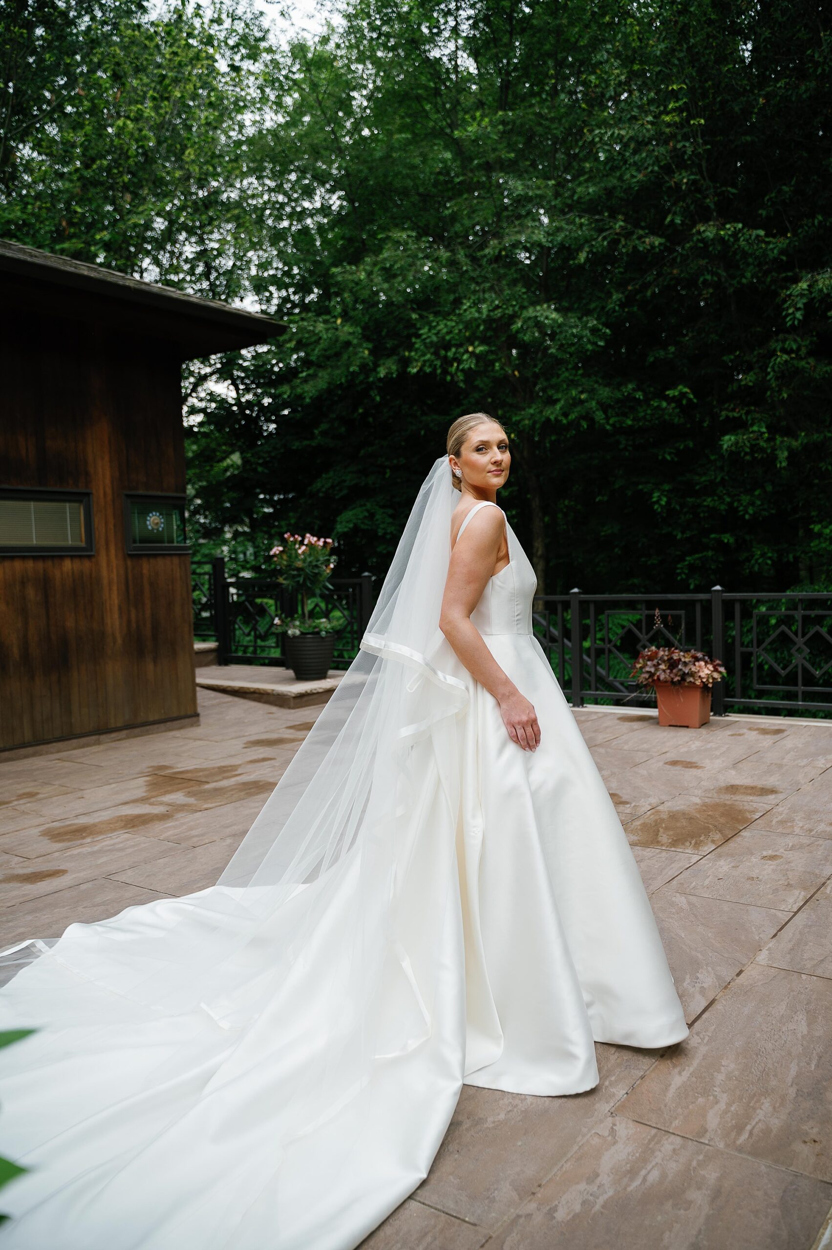 bride looks over shoulder in wedding gown outside home